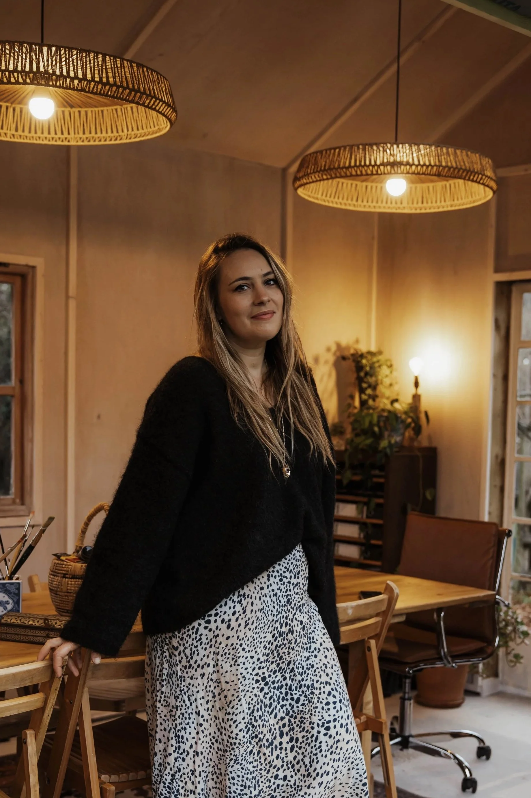 Hannah Taylor-Matthews, founder of A Creative Pause, stands at her workshop studio door, smiling at camera