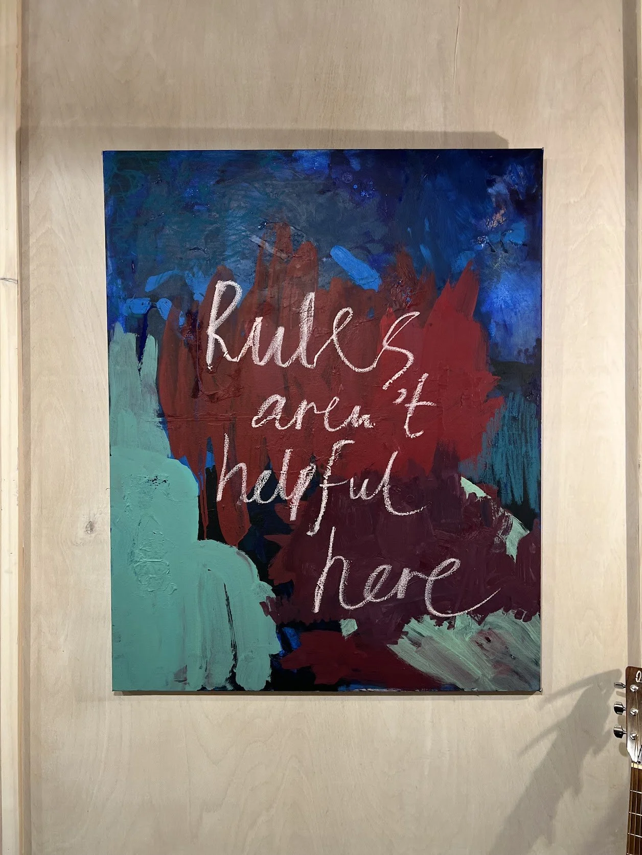 Colorful abstract painting on wall with the phrase "rules aren't helpful here' on my studio wall