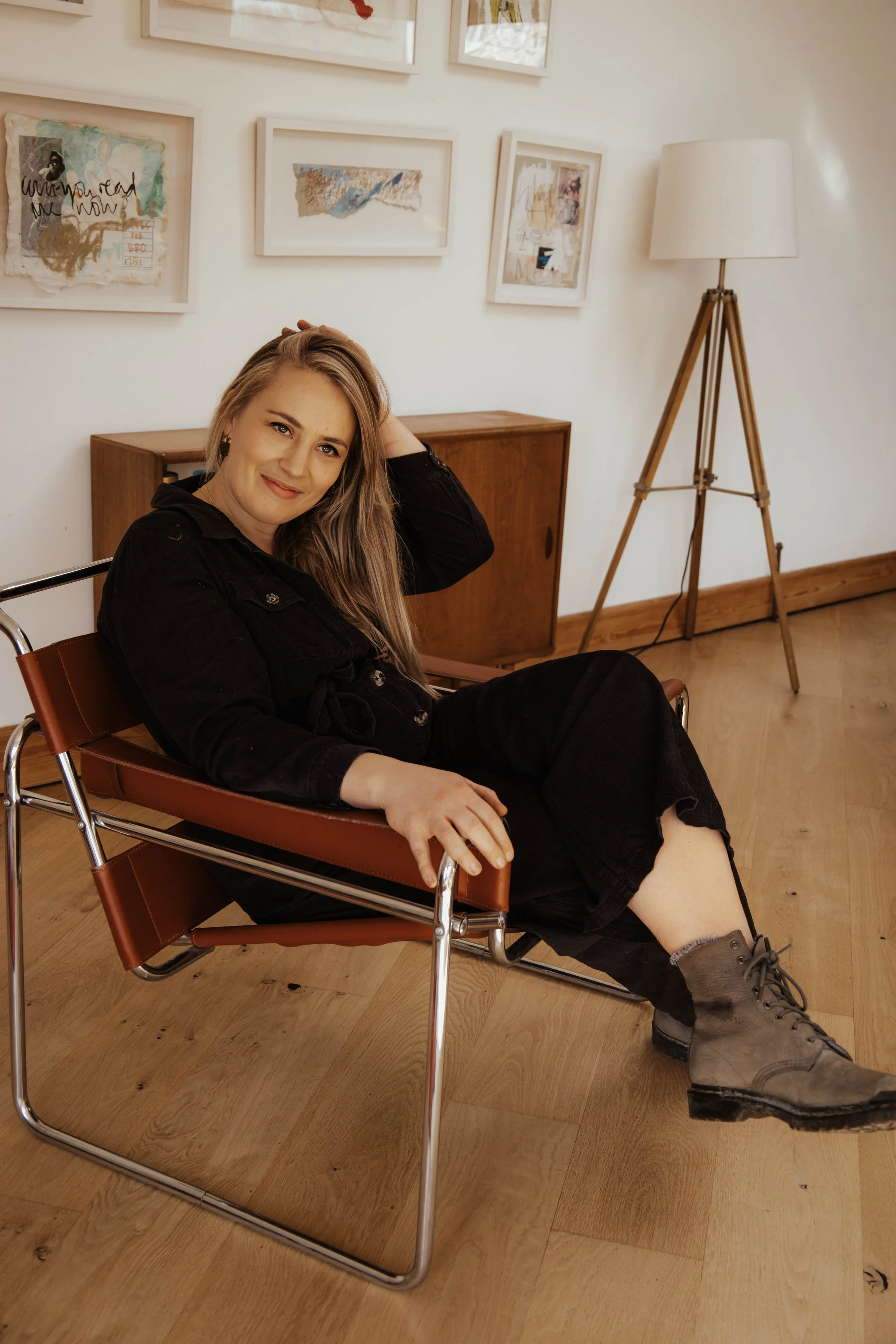 Hannah Taylor-Matthews, founder of A Creative Pause sitting on a desk chair in her garden workshop studio,, smiling and looking at the camera.