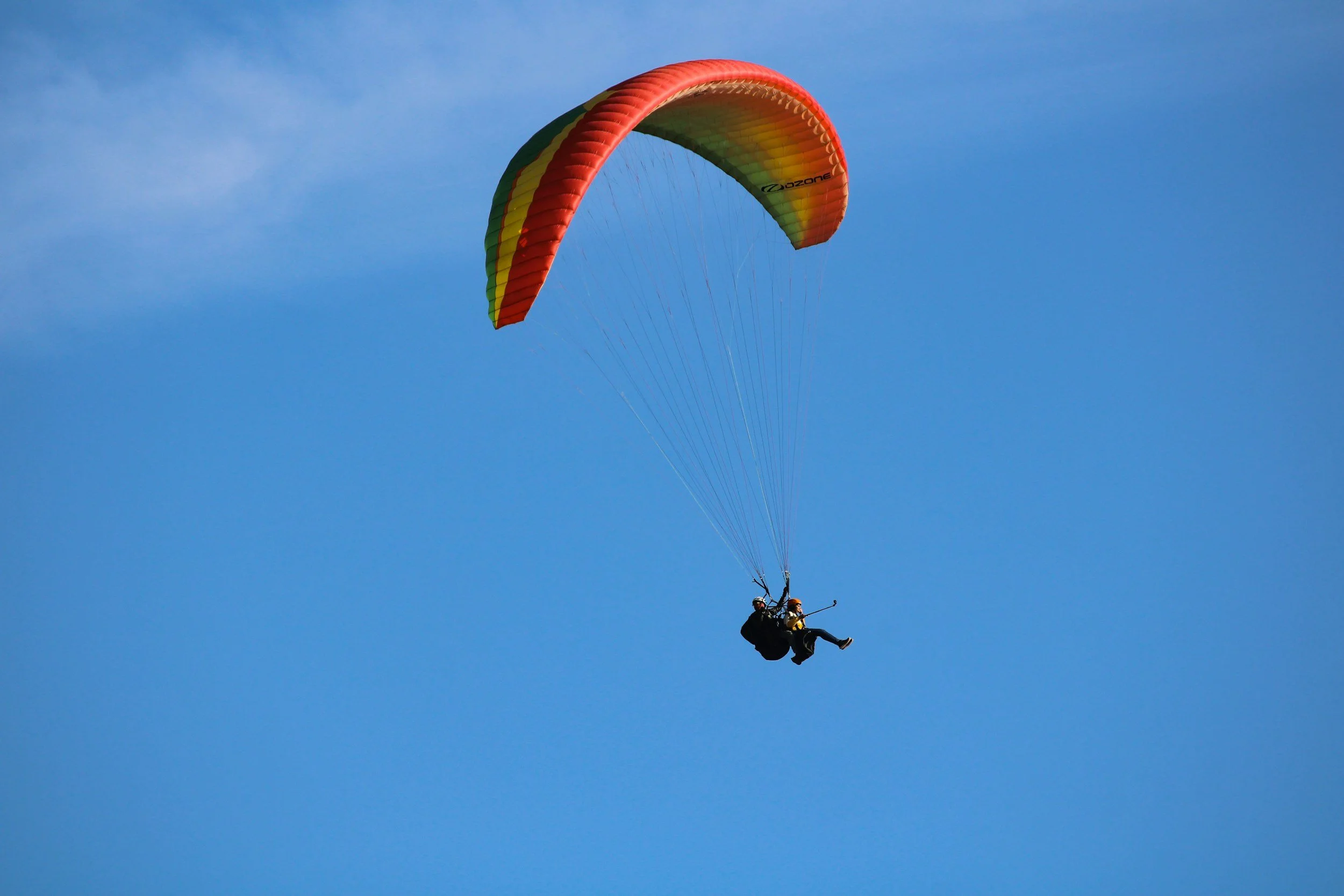 Deux personnes en parachute volant dans un ciel bleu clair.