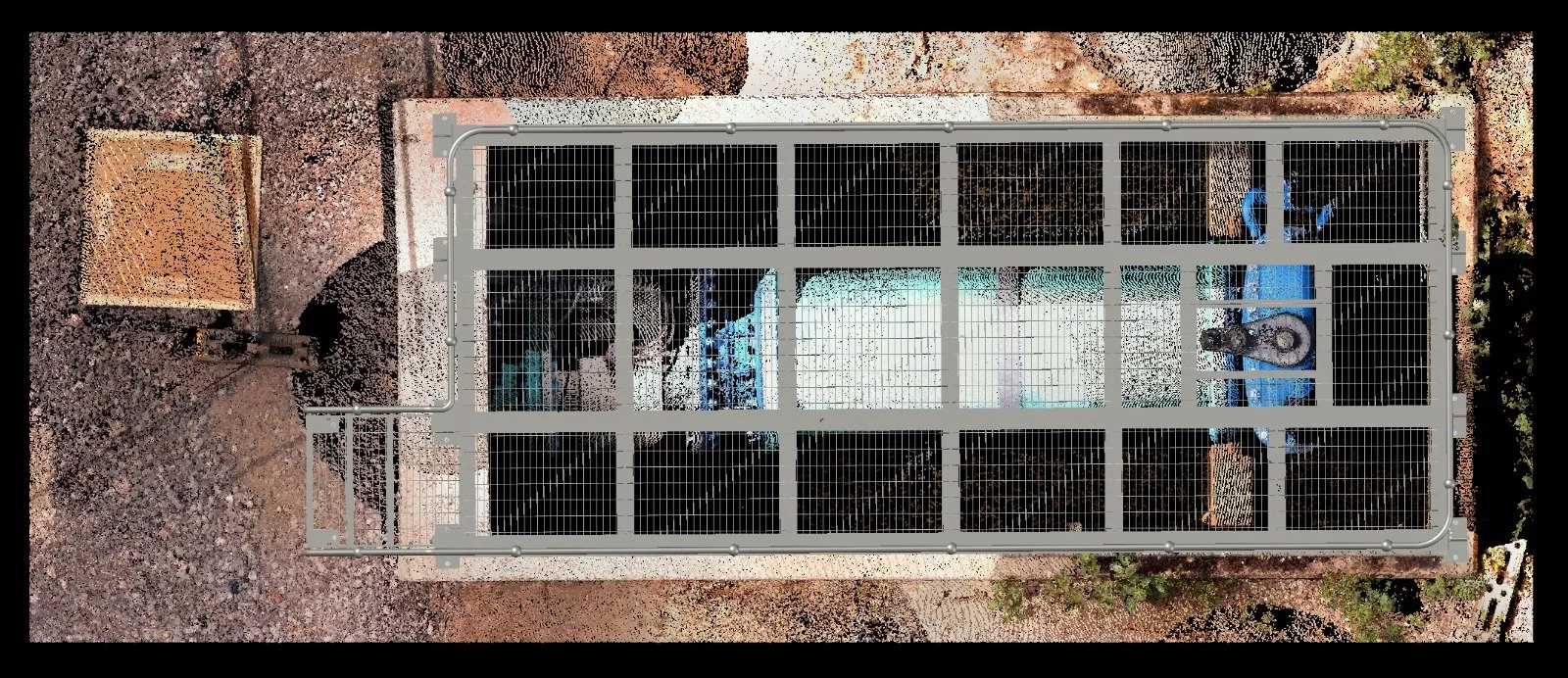 Top-down view of a fenced, cage-like structure with a water trough inside, placed on a concrete pad in a dirt yard.