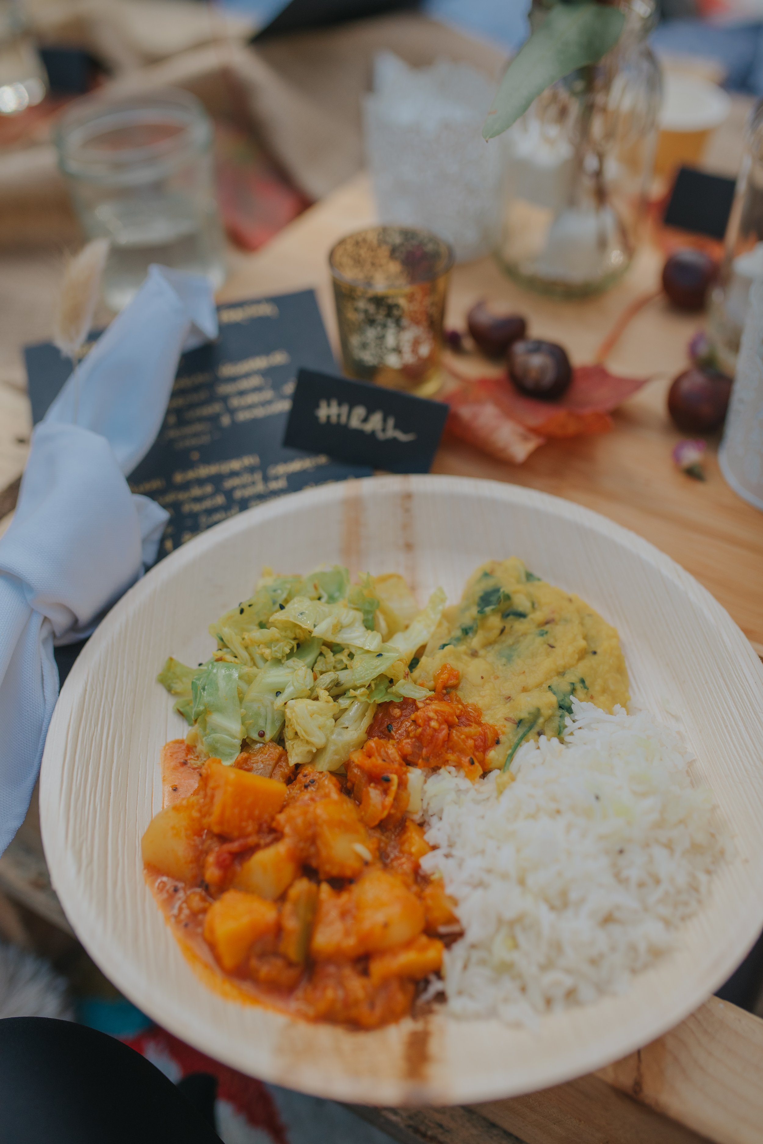 A plate of Indian food with rice, vegetables, and lentils on a wooden table.