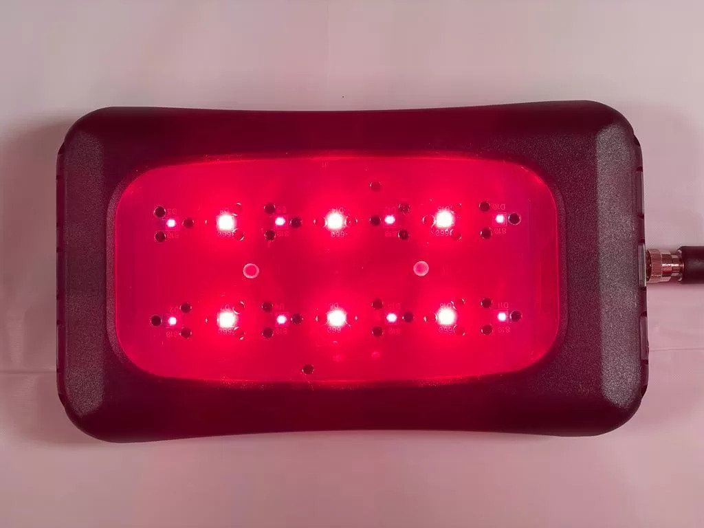 A rectangular Red Light device by LZR UltraBright with a black border and a red illuminated grid of LEDs on top. There is a coaxial cable connected to the right side of the device.