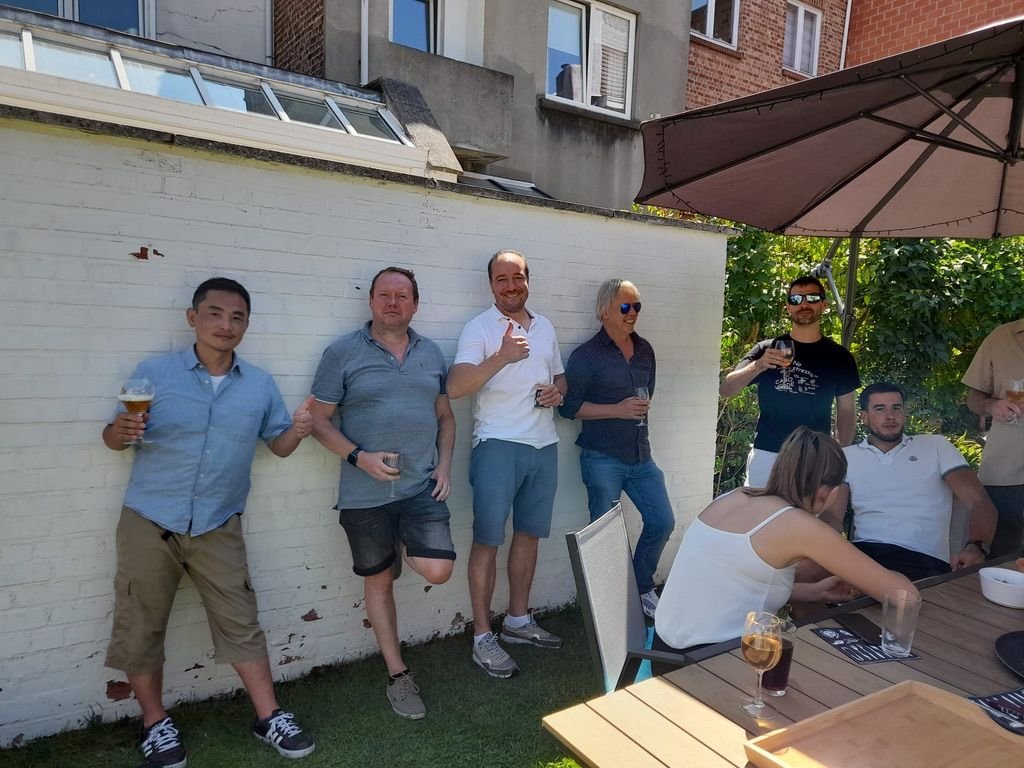 Groupe de personnes profitant d'une fête en extérieur, avec une table, un parasol, et des boissons