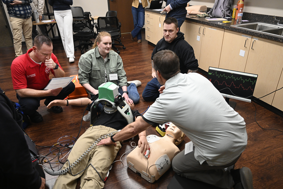 Workshop attendees conduct a simulation of mechanical CPR on a medical mannikin. The mannikin is wearing an INSIGHT-CPR prototype on its wrist.