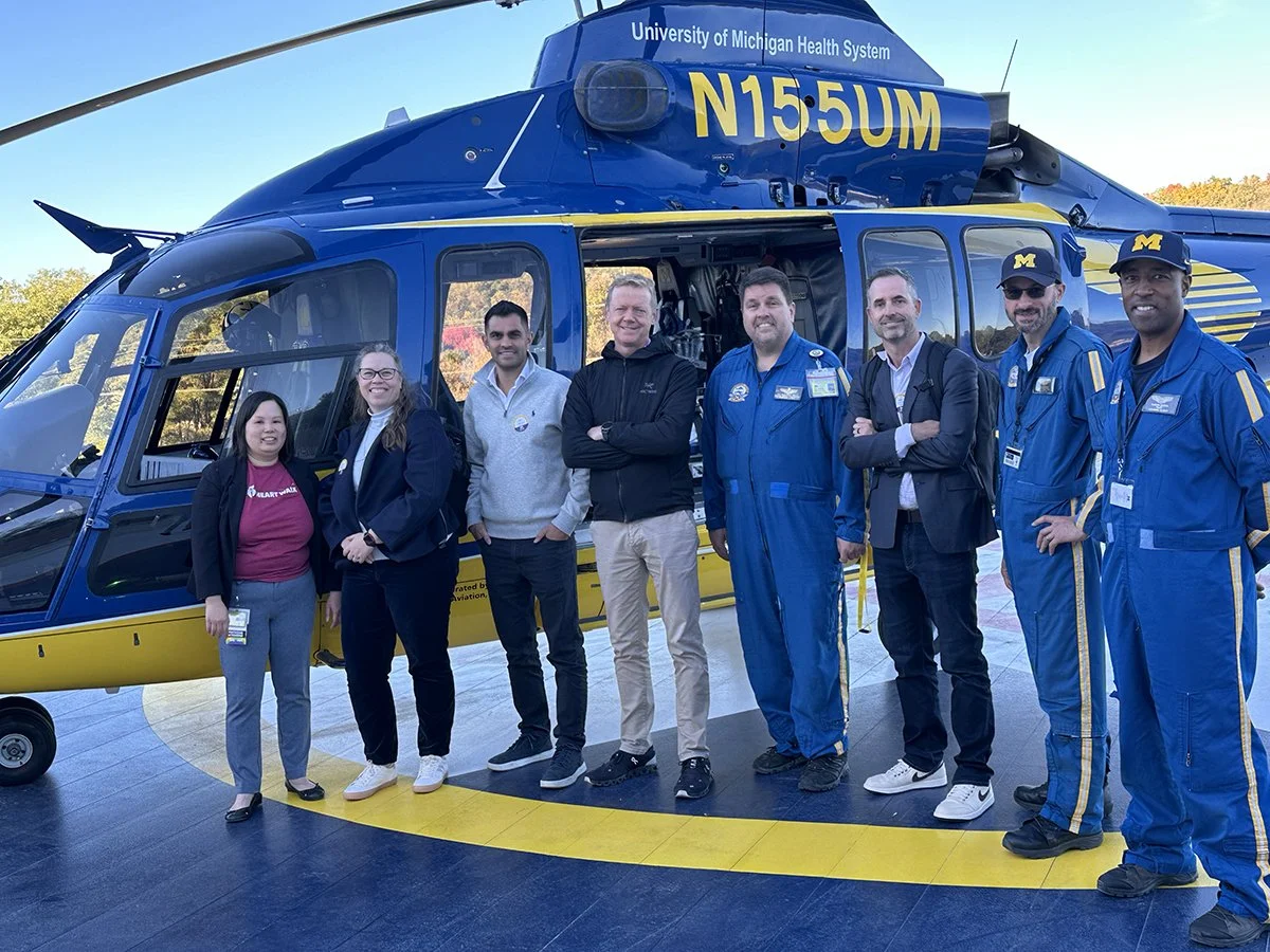 Dr. Cindy Hsu, Juliet Rogers, Dr. James Price, Dr. Paul Rees, and Aaron Call stand with members of the University of Michigan's Survival Flight critical care air transport team in front of one of Survival Flight's helicopters.