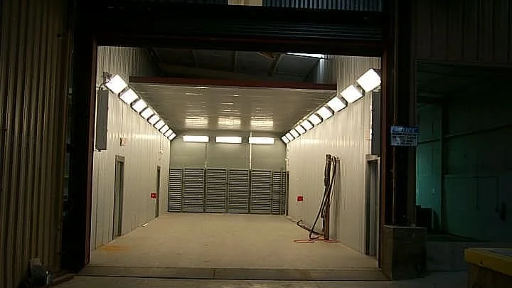 An empty industrial truck bay or storage unit with bright overhead lights and metal walls.