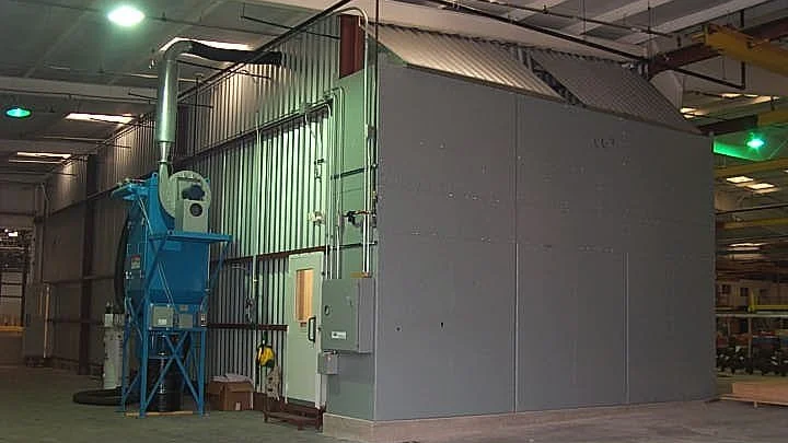 Industrial processing or manufacturing facility with large metal structure and control panels inside a warehouse.
