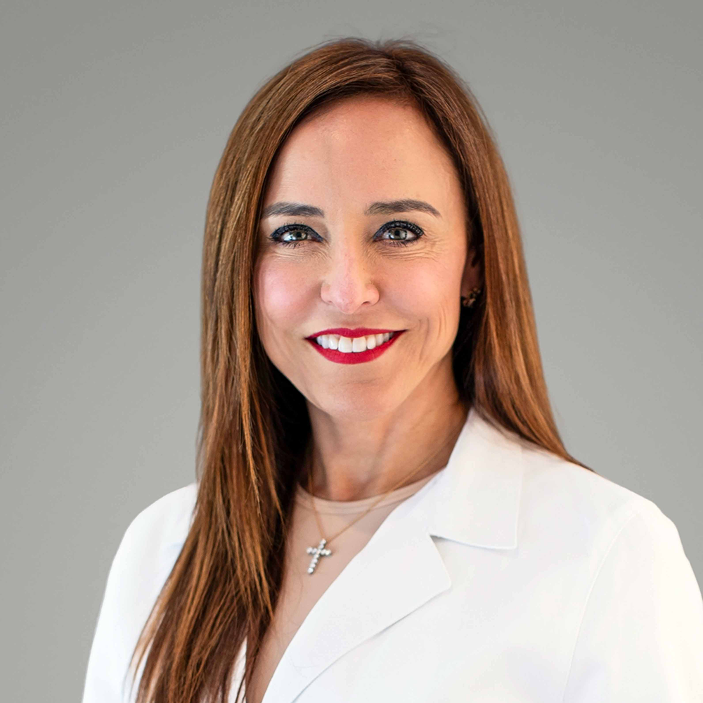 Headshot of Dr. Hebe Diaz wearing a white blazer and a cross necklace, smiling at the camera.