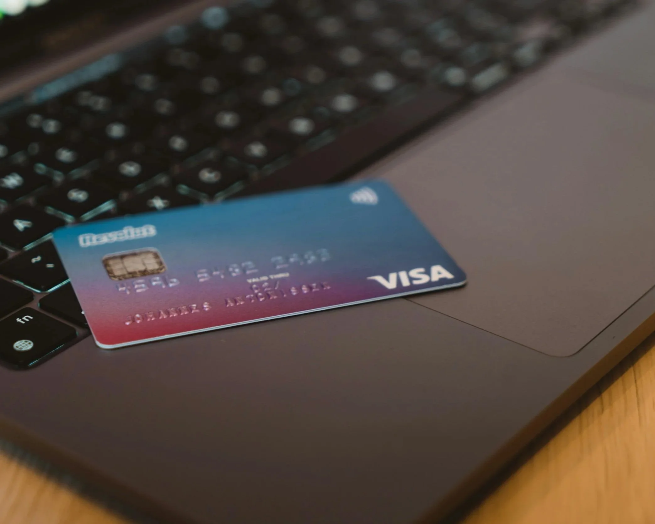 Close-up of a Visa credit card placed on a laptop keyboard with a blurred background.