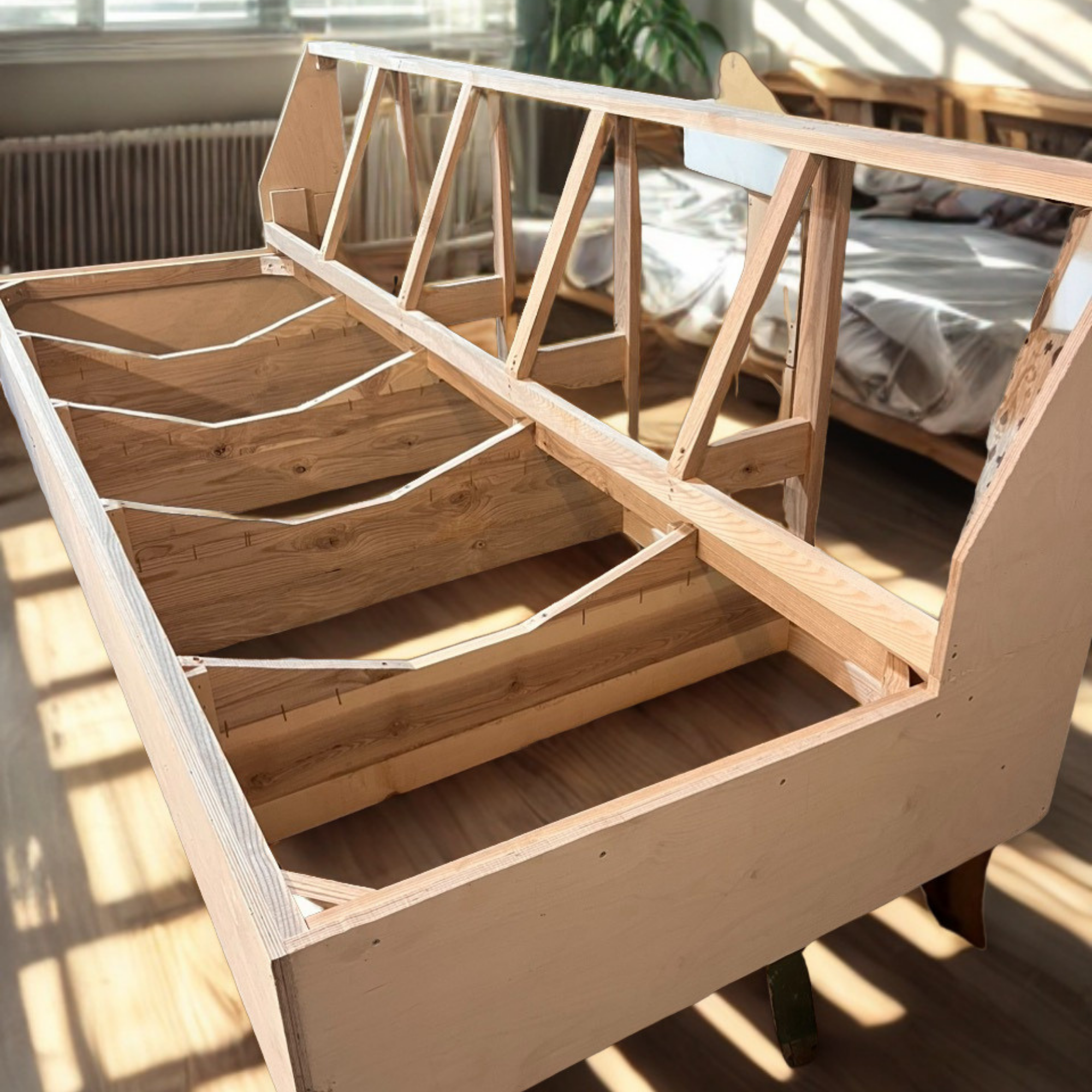 Unfinished wooden bed frame under construction with slats and support beams, indoors with sunlight and a blurred bed in the background.