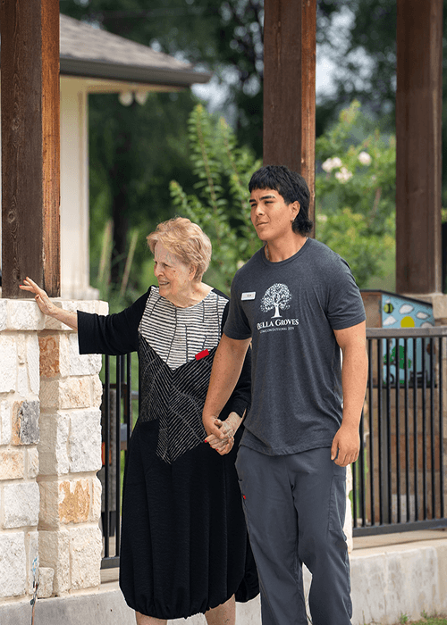 A Bella Groves caregiver walking hand in hand with a resident, providing compassionate memory care and personalized support in Bulverde, Texas.