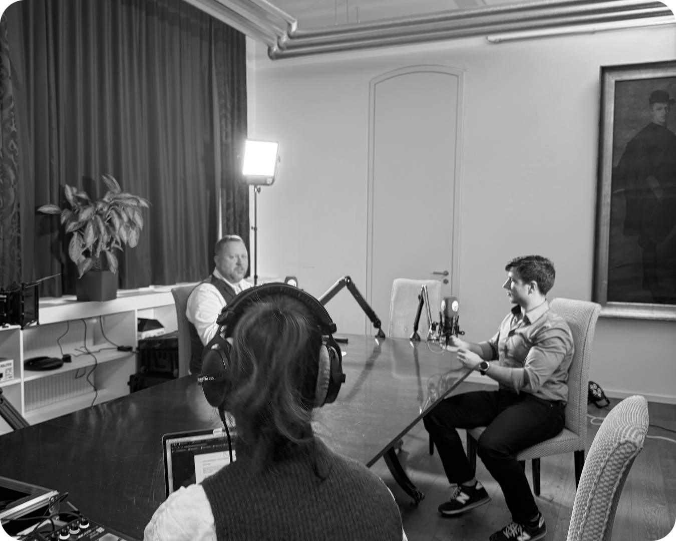 Menschen, die in einem Raum mit einem Tisch und Aufnahmegeräten eine Podcast-Aufnahme machen.