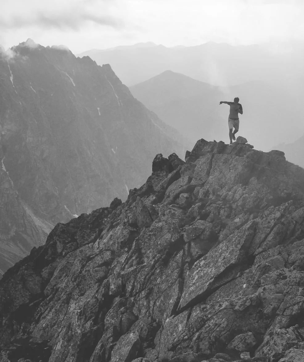 Personne debout au sommet d’une montagne illustrant la prise de hauteur, la vision et la performance