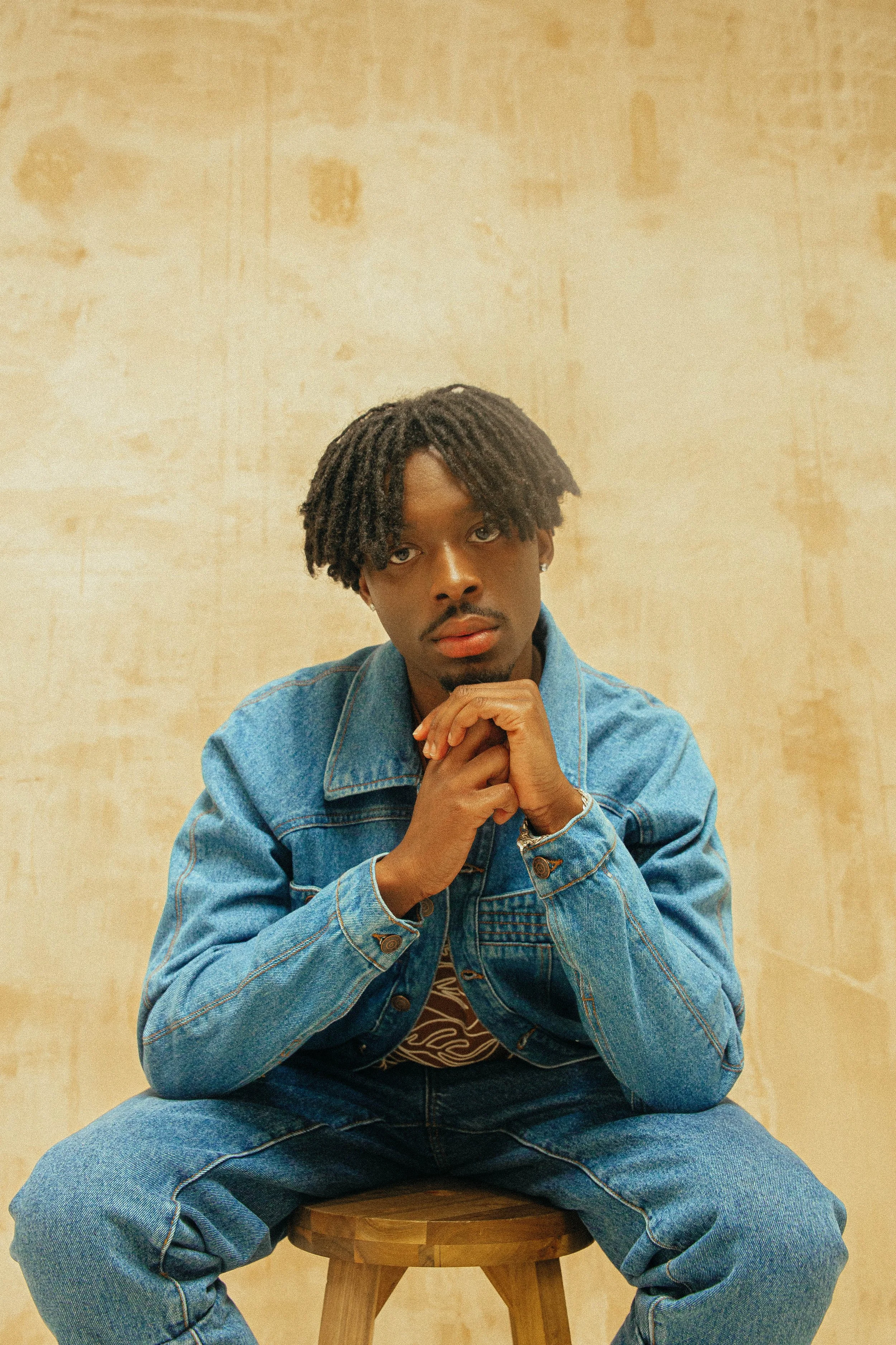   Images Above, Sheyi Cole wears: Qasimi, Brown Hackmanite Single Jersey Artist T-Shirt | Purple PR, Jacket: Demin Horde Studio, Jeans: Aken Jeans Horde Studio | Black PR  