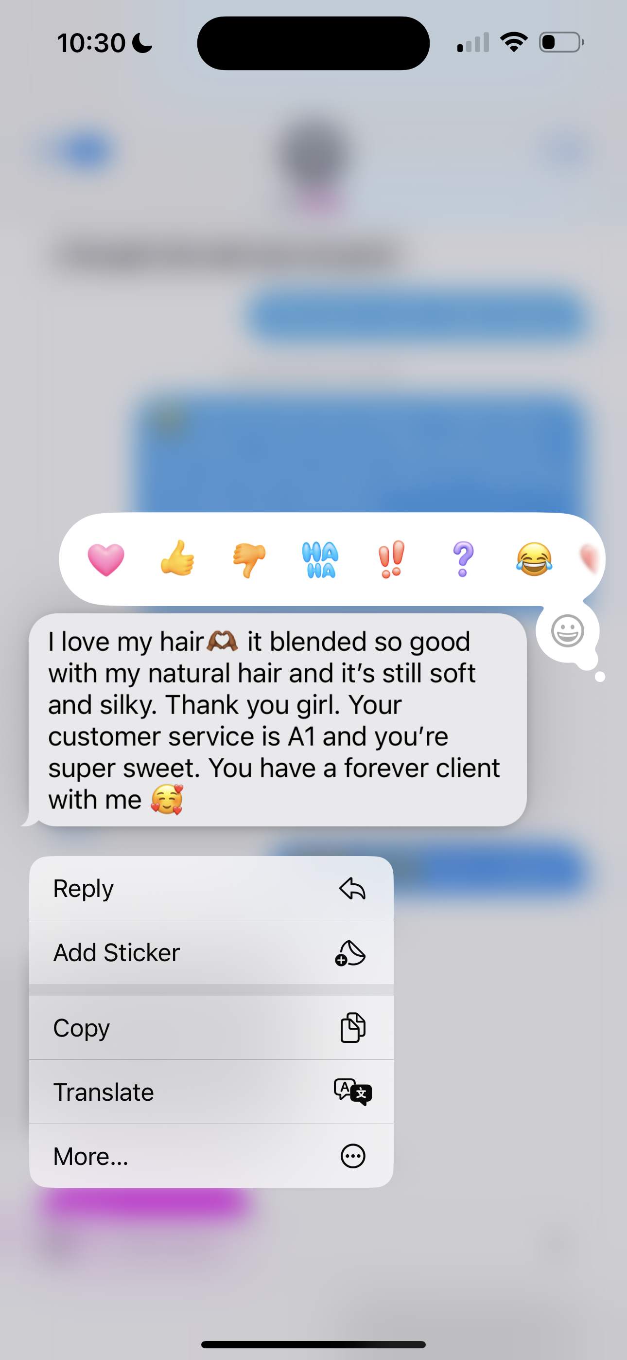 Close-up of a smartphone screen displaying a messaging app with a conversation about hair care, along with emoji stickers and options to reply, add sticker, copy, translate, or more.