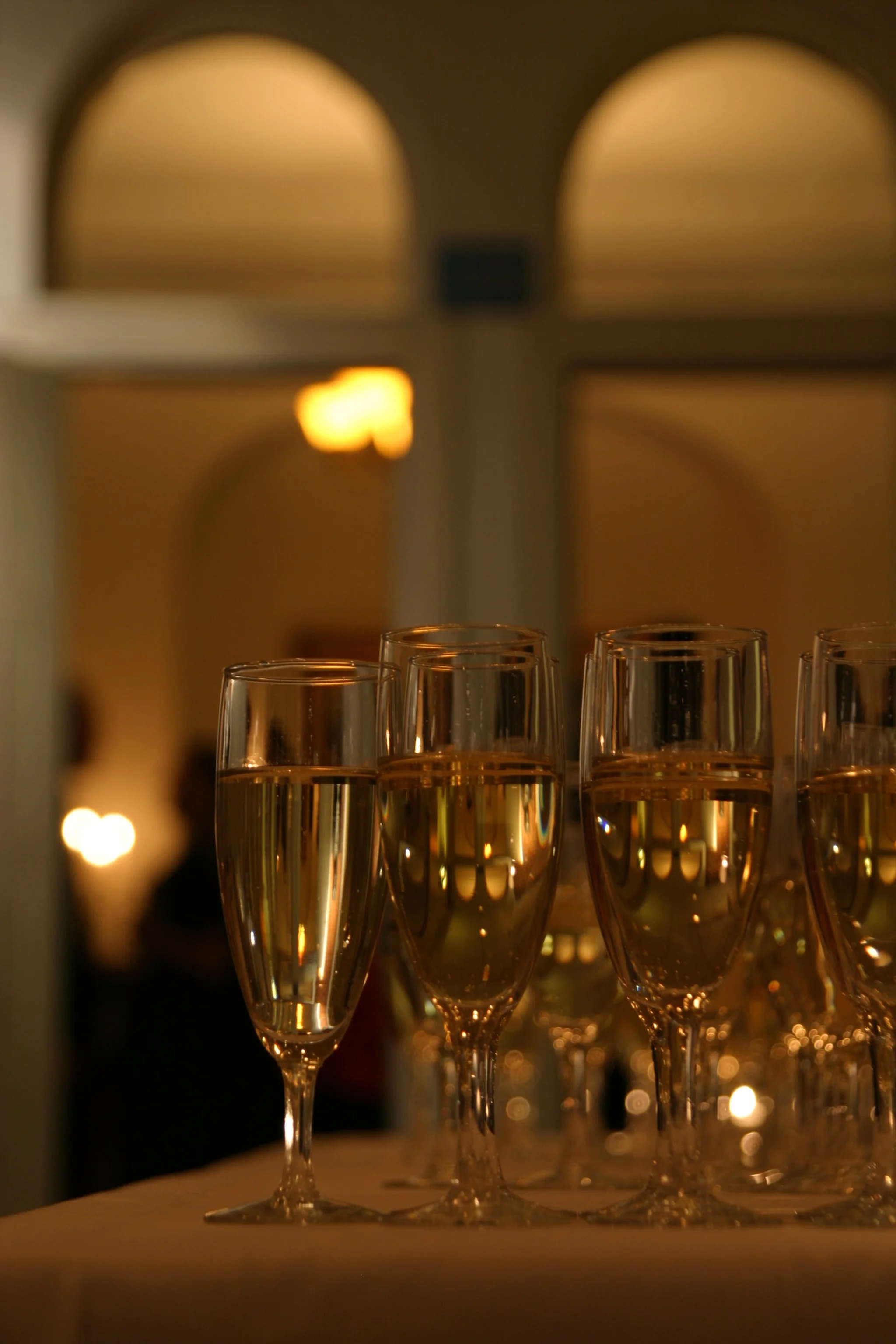 Flera champagneglas står på ett bord med ett mörkt och varmt bakgrundsbelysning, vilket skapar ett festligt och elegant atmosfär.