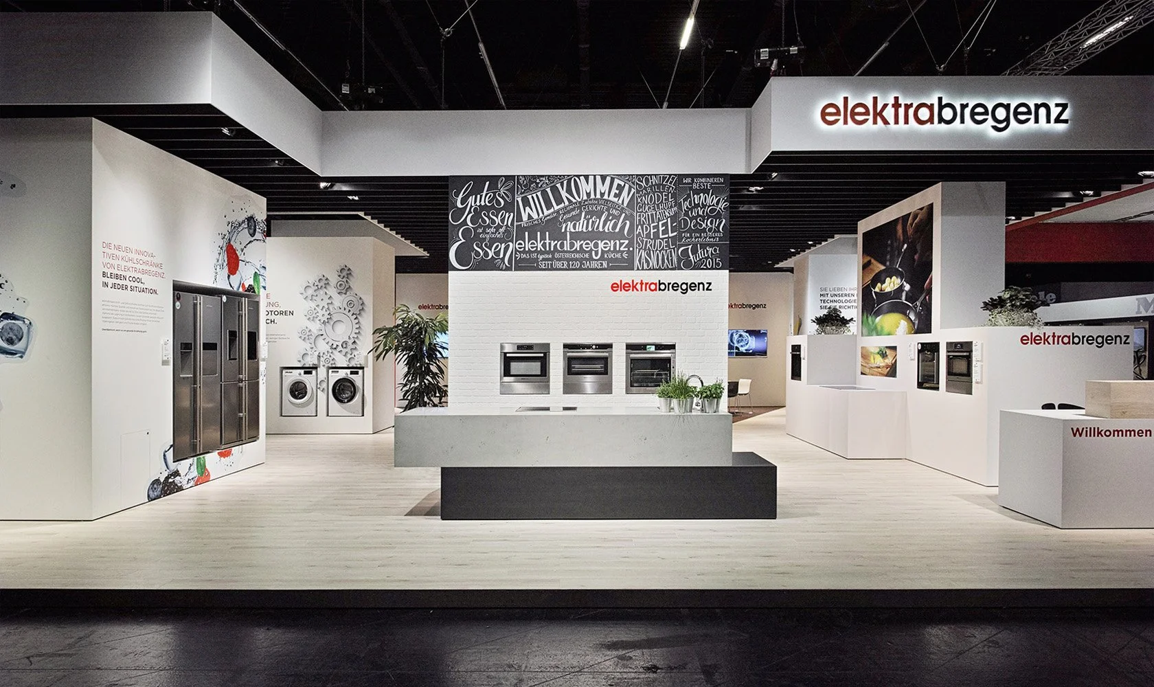 Interior view of an appliance store with washing machines, refrigerators, and ovens on display. The store has modern decor with white walls, black ceiling accents, and red and black signage reading "elektrabregen".
