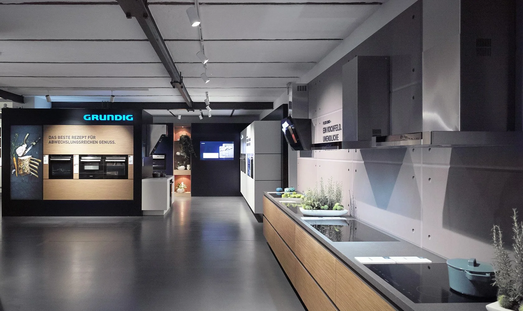 Showroom with kitchen appliances and design displays, including ovens and kitchen countertops, in a modern store setting.