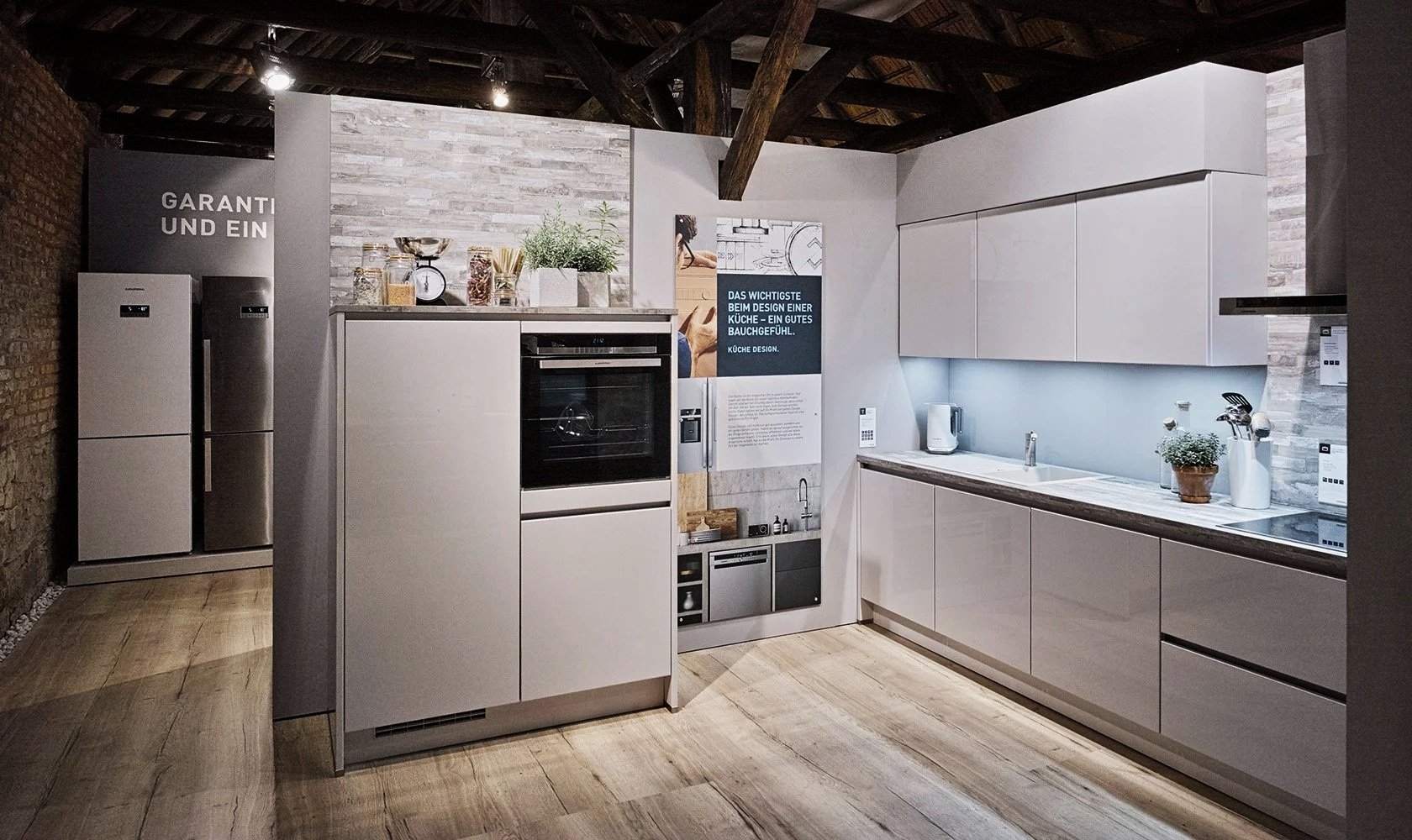 Modern kitchen with white cabinets, wooden flooring, and brick walls, featuring appliances and decorative plants.