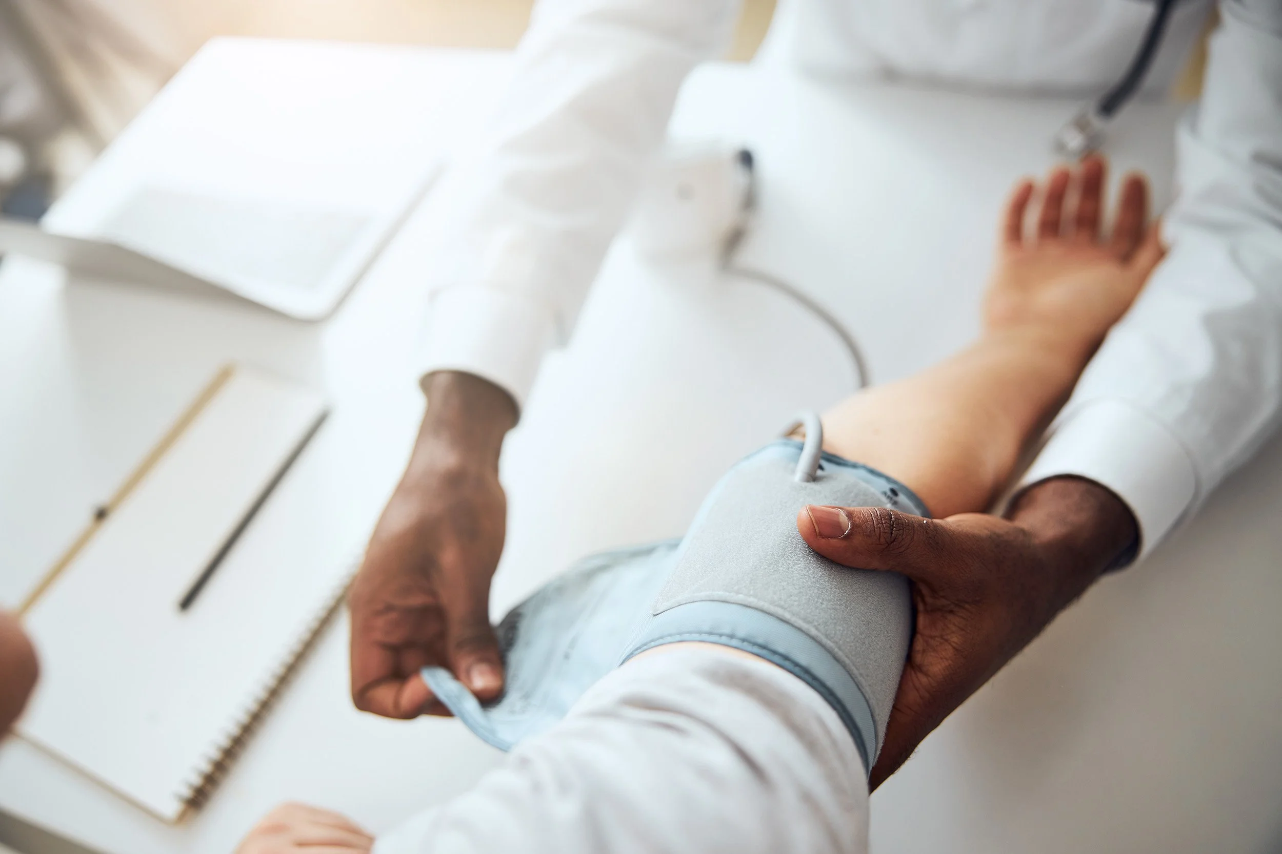 A person lying on a medical examination table, with a healthcare professional using a device to check their leg.