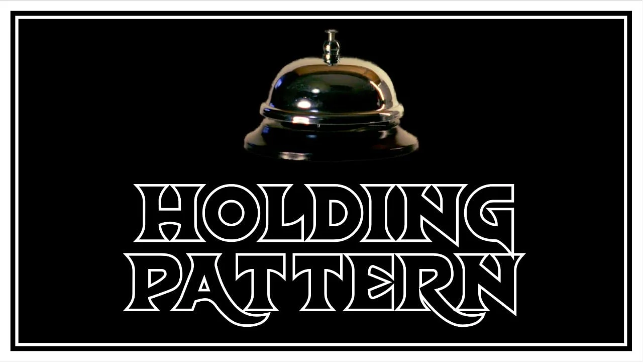 A black background with a shiny chrome bell at the top center. Below the bell, in large stylized white text, are the words 'HOLDING PATTERN'. The image has a white border around it.