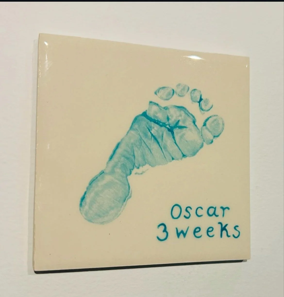 Artwork of a baby's foot with the text "Oscar 3 weeks" written next to it.