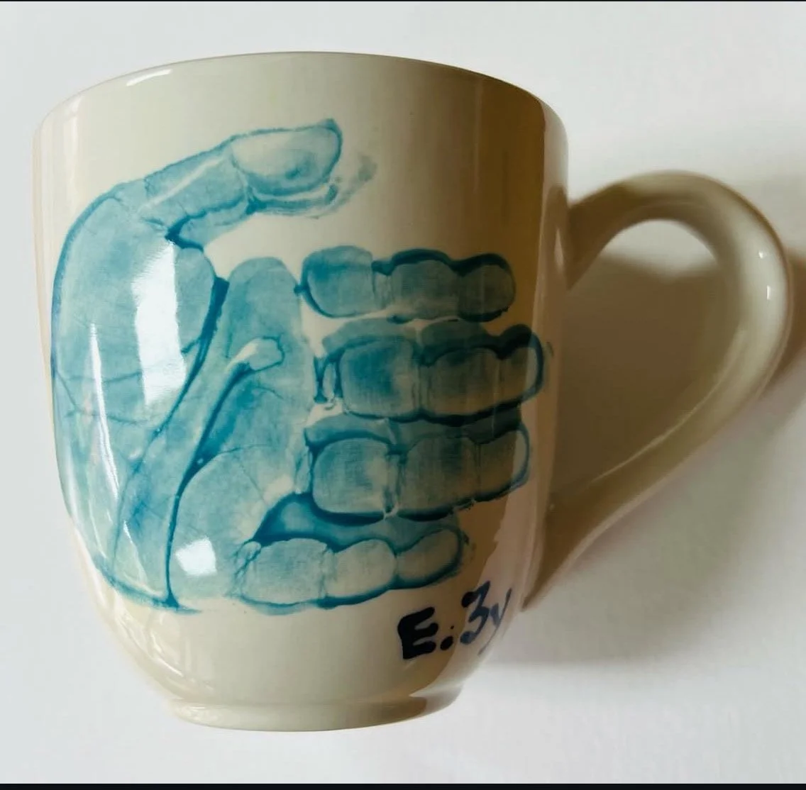 A coffee mug with a blue illustration of child's hand with name.