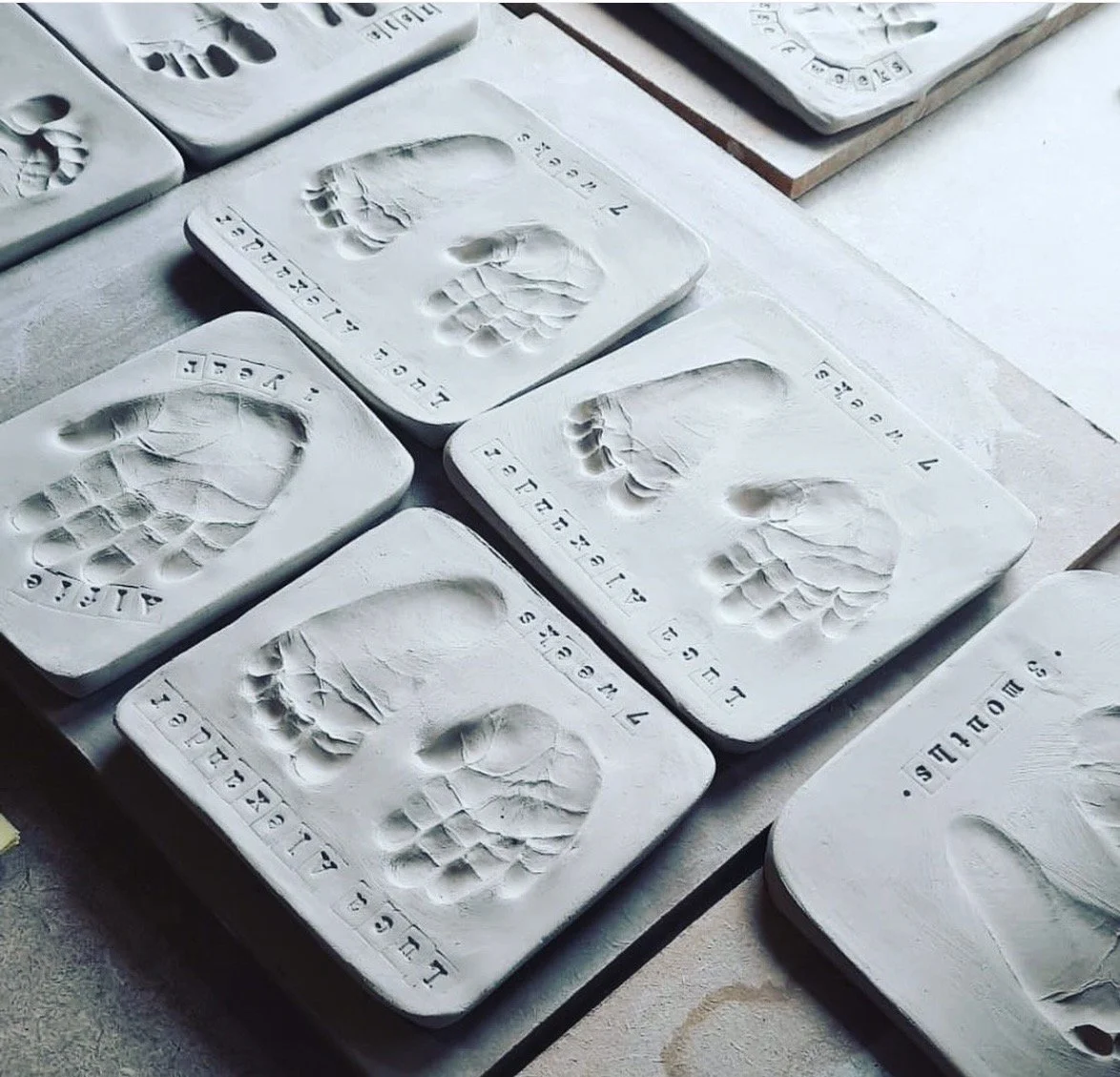 Multiple dried clay imprints that have been personalised with name and age and waiting to go into kiln to be fired.