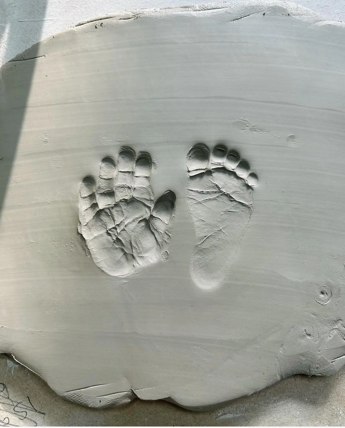 Clay imprint of a child's handprint and footprint.