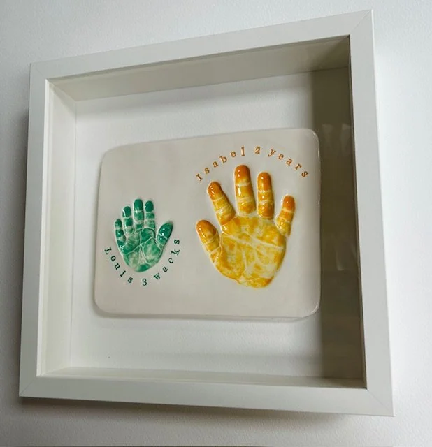 Square wall shadow box containing a keepsake with two painted handprints with personalised names and ages.