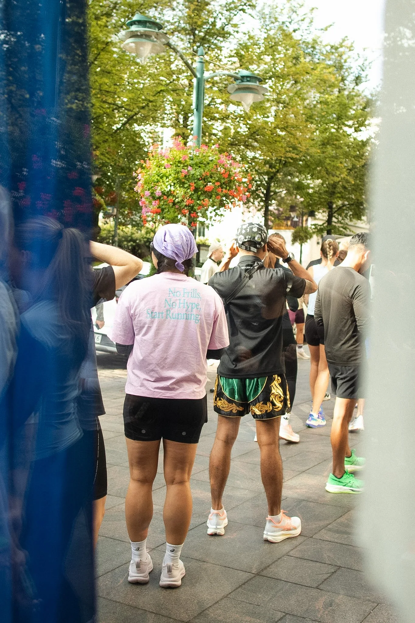 People gathered outdoors in athletic attire, preparing for a run, with trees and street lamps in the background.