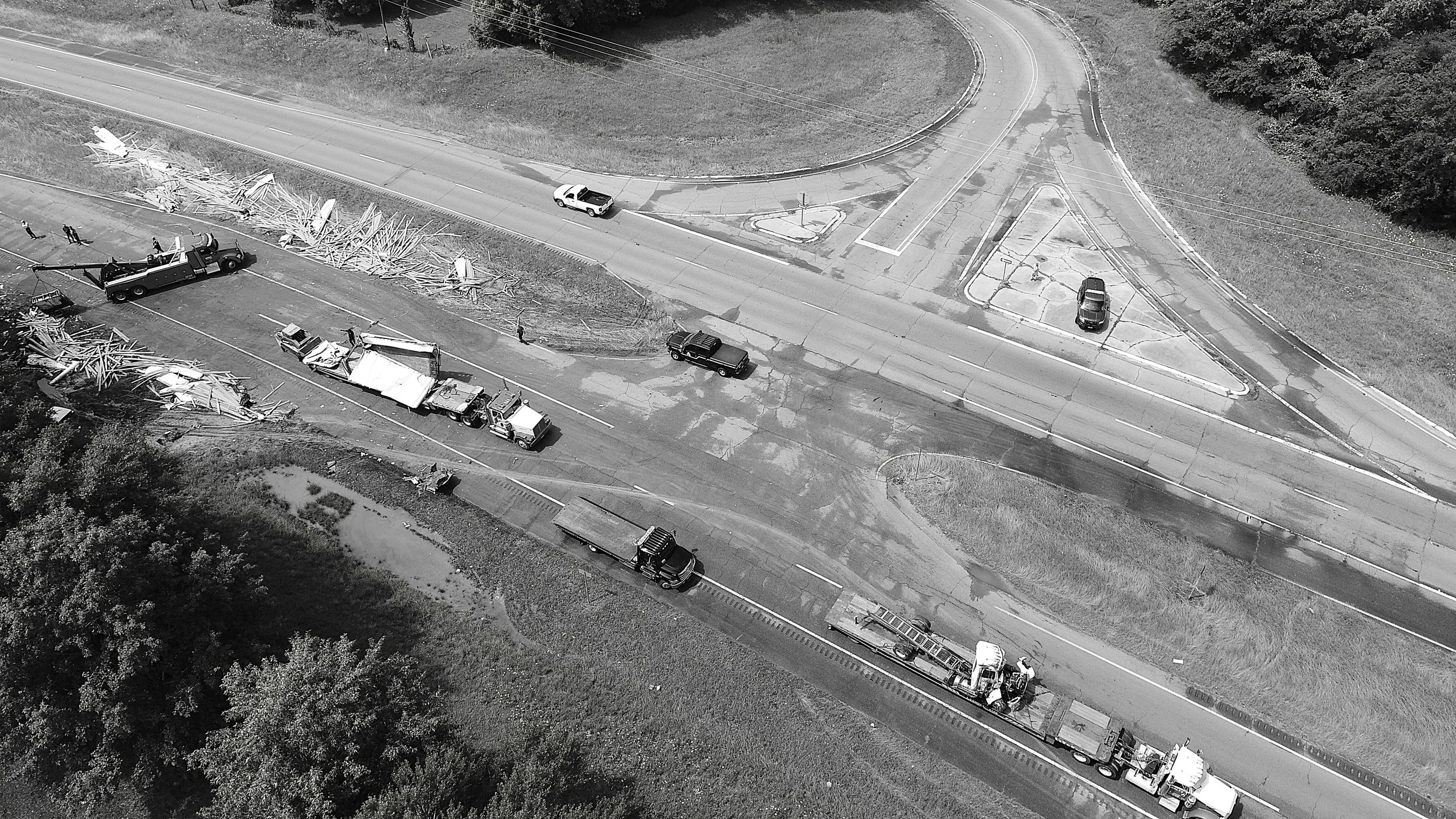 Aerial view of a multi-vehicle accident involving trucks with debris scattered on a highway, with a squad of emergency responders.