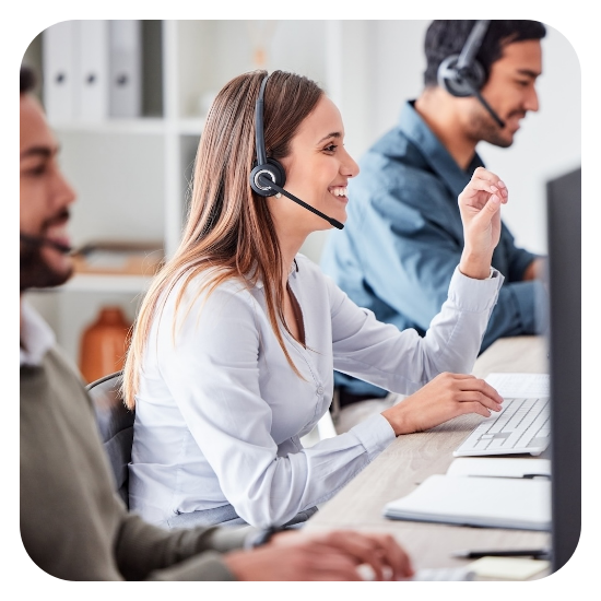 Customer service representatives wearing headsets working at computers in an office.