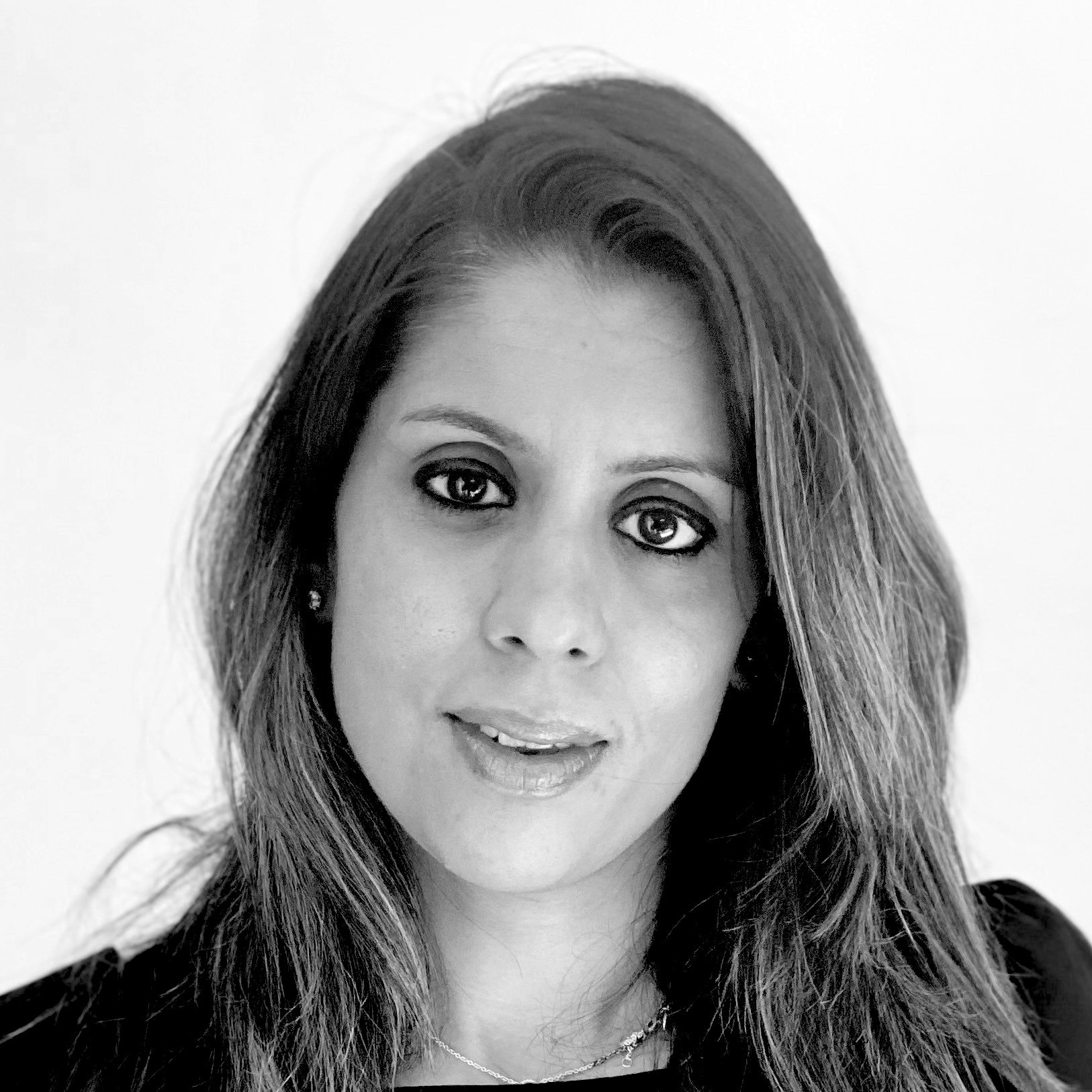 A black and white portrait of a woman with long hair, wearing eye makeup, earrings, and a necklace.