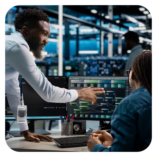 Male technician explaining data on computer screen to a woman in a data center.