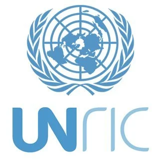 United Nations logo with a world map surrounded by olive branches and the abbreviation 'UNRIC' beneath it.