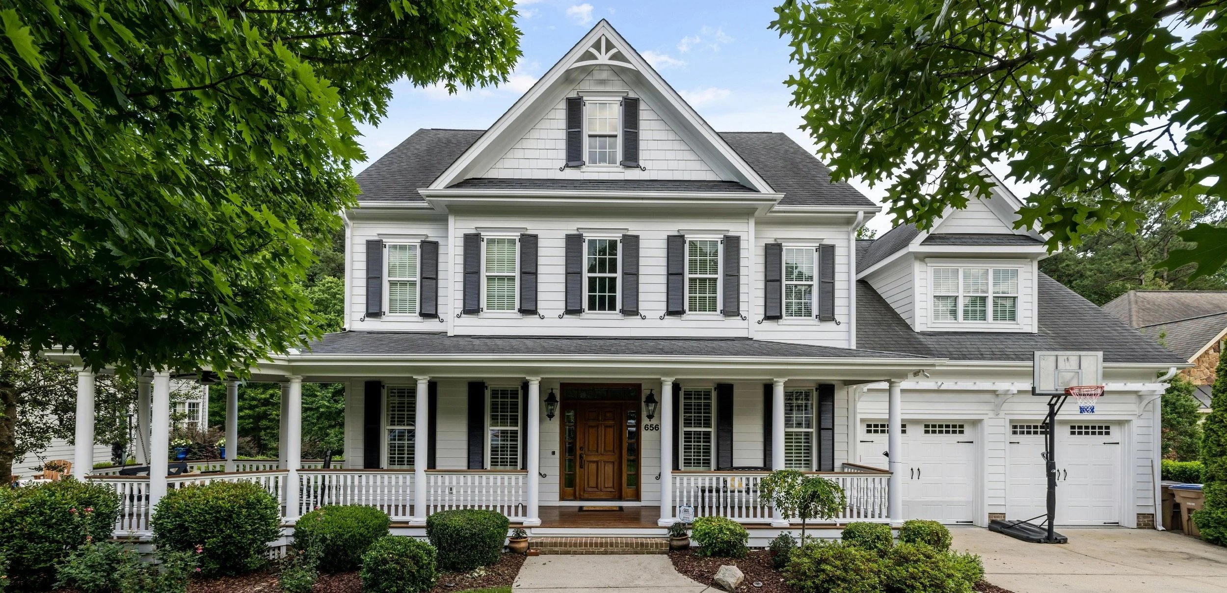 Front view of modern CT/NY house with a large front porch and landscaped yard.