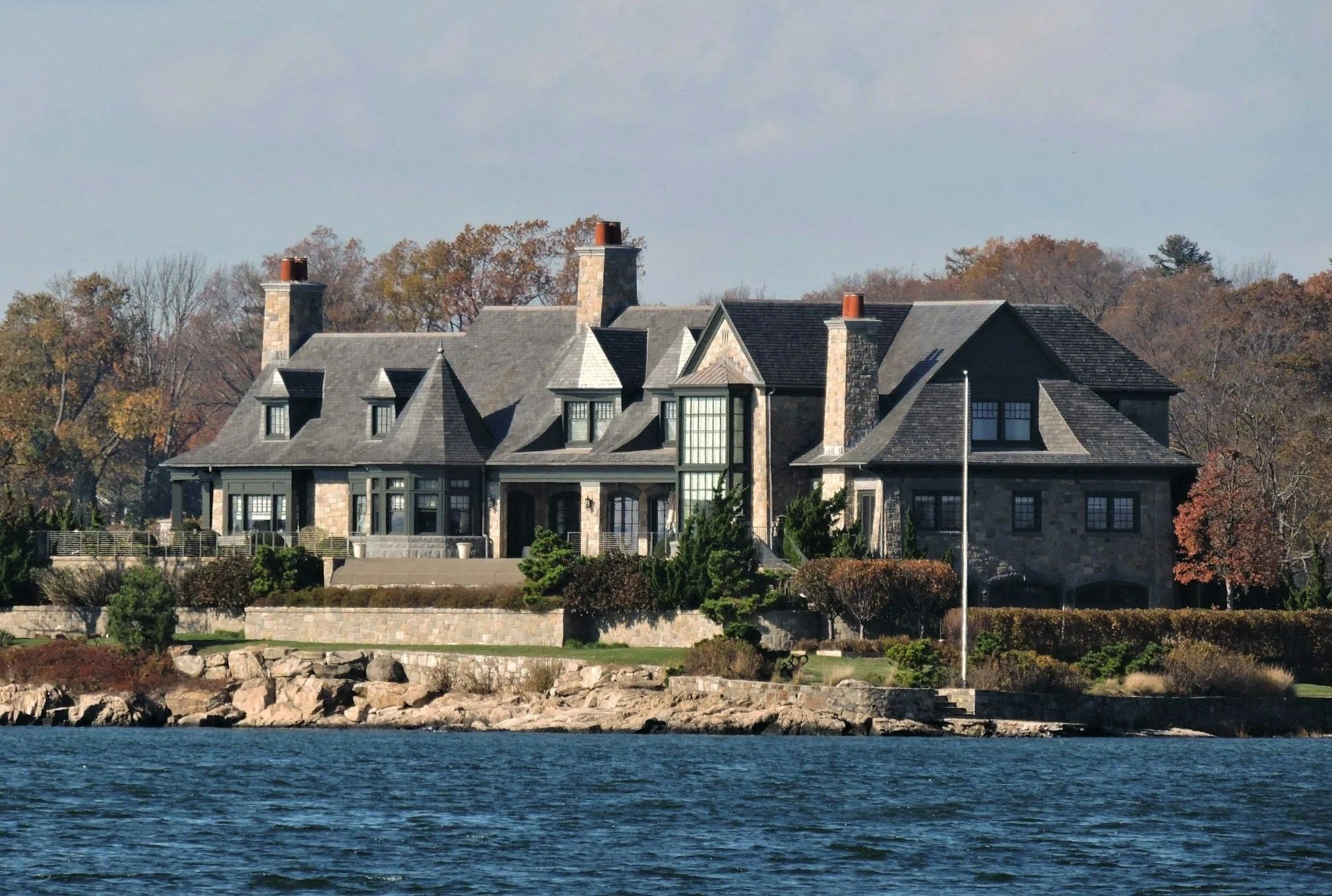 Front view of luxury CT/NY property on the water surrounded by trees.