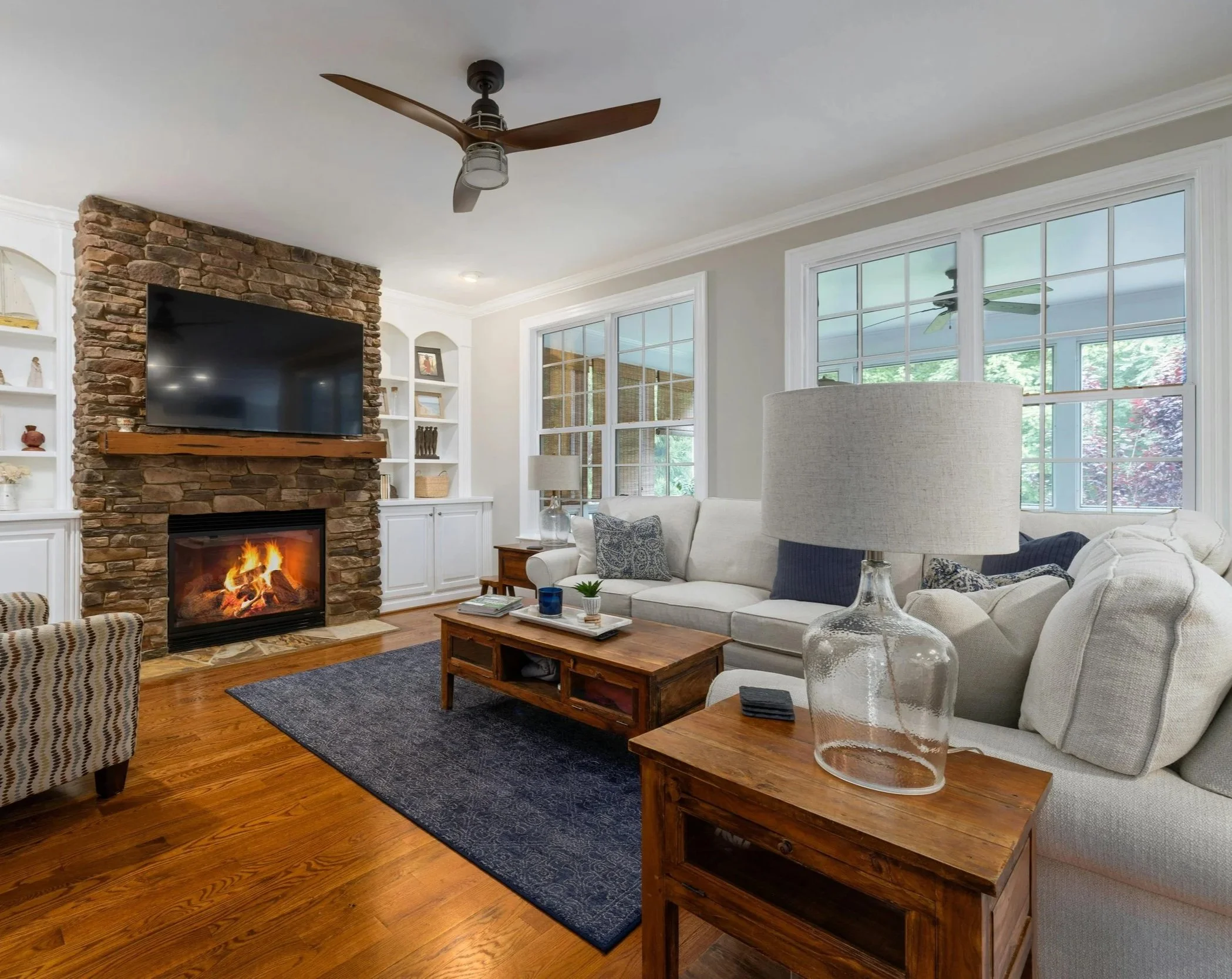 Modern, relaxing living room with a stone fireplace overlooking the back deck