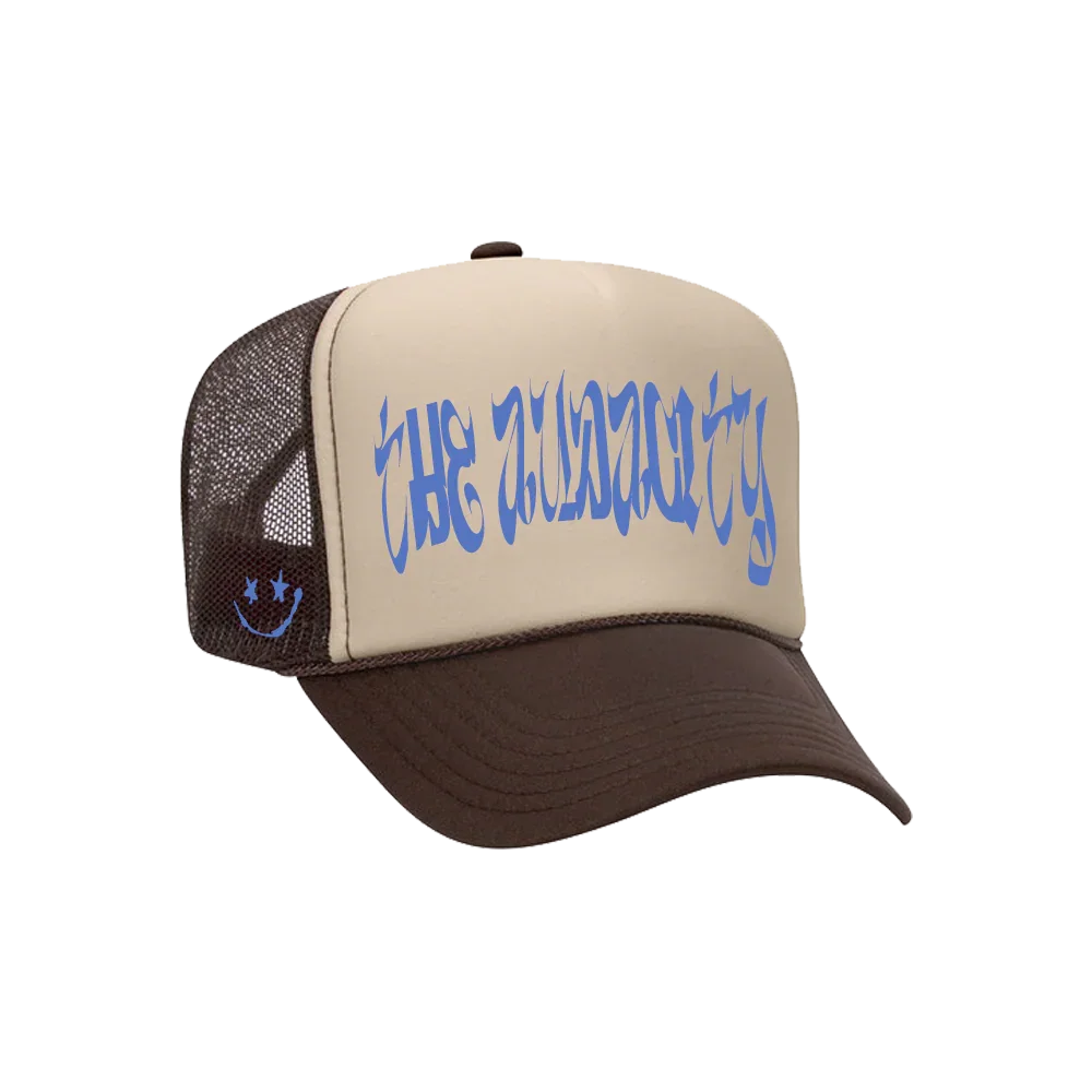 Trucker cap with brown brim, beige front panel, black mesh side panels, blue text reading 'THE GUNSLINGER' and a small blue smiley face with X eyes on the side.