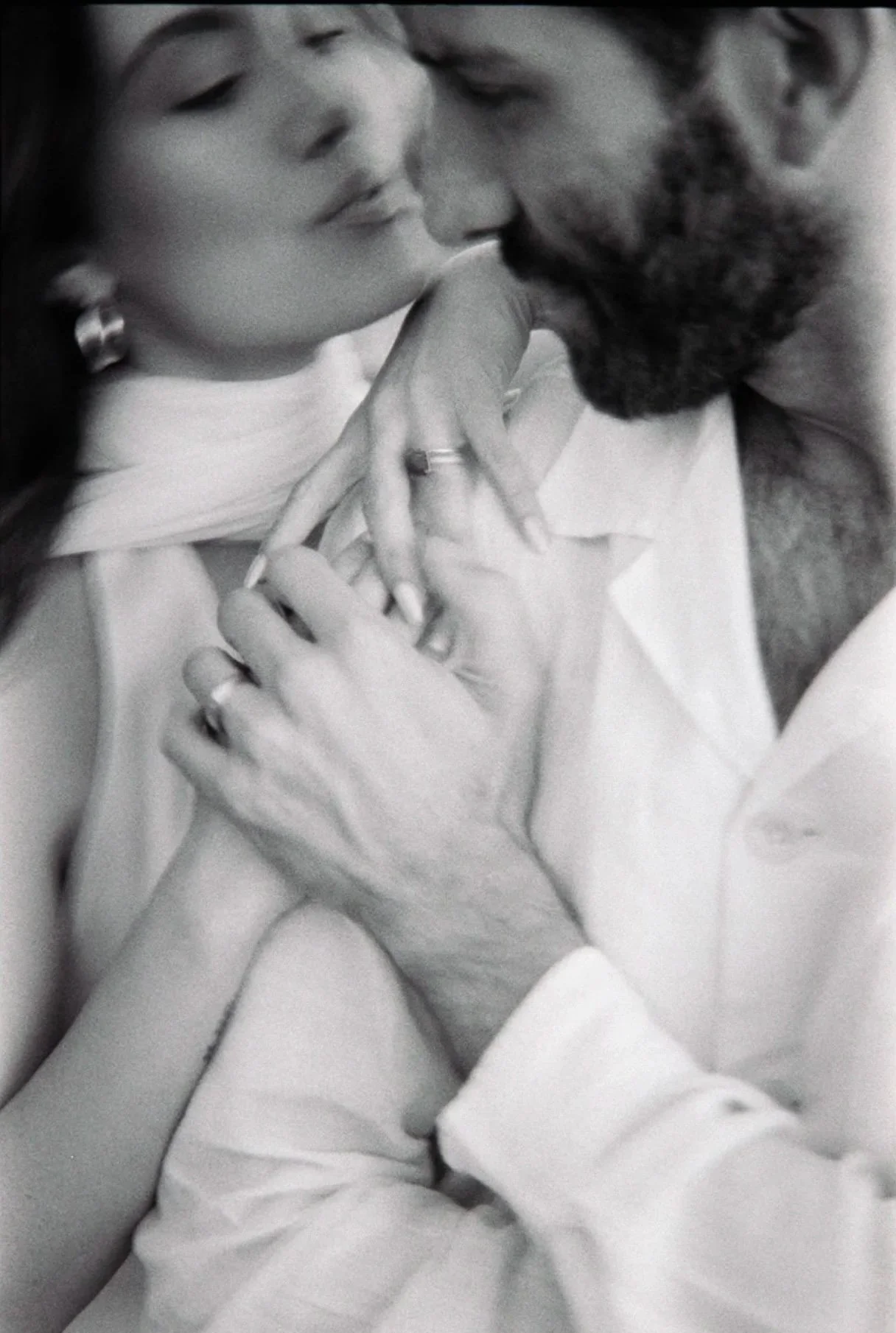 A black and white photograph of a couple embracing intimately, with their foreheads touching and eyes closed, sharing a tender moment.