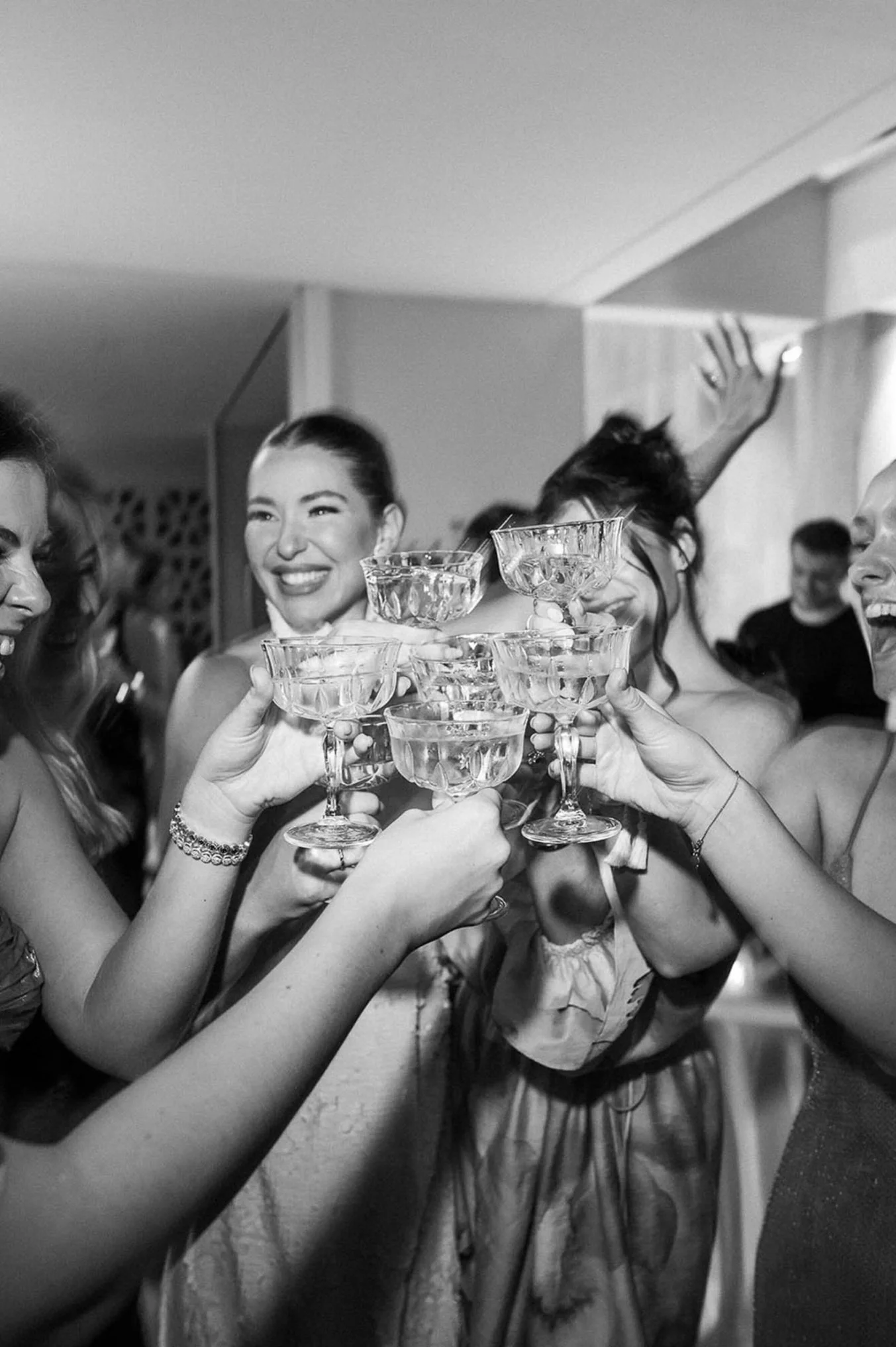 A group of women celebrating with glasses of champagne, smiling, and raising their glasses together at a party.