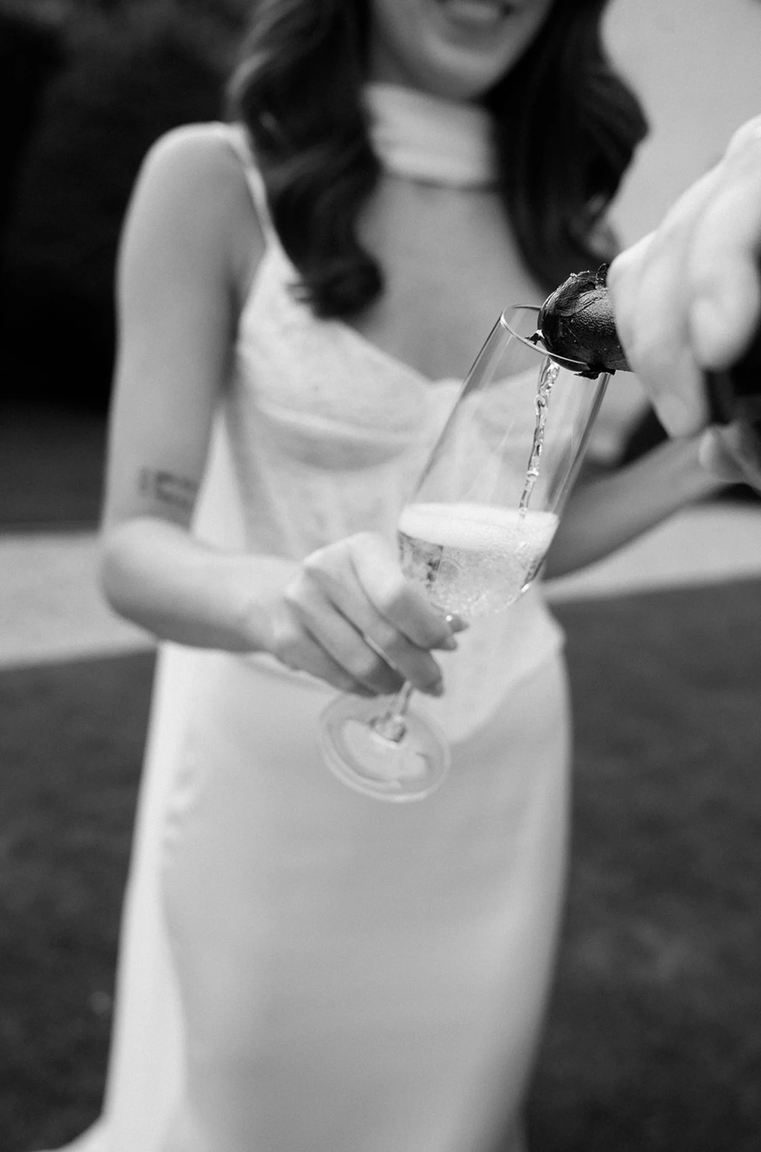 A woman in a wedding dress pouring champagne into a flute at a wedding celebration.