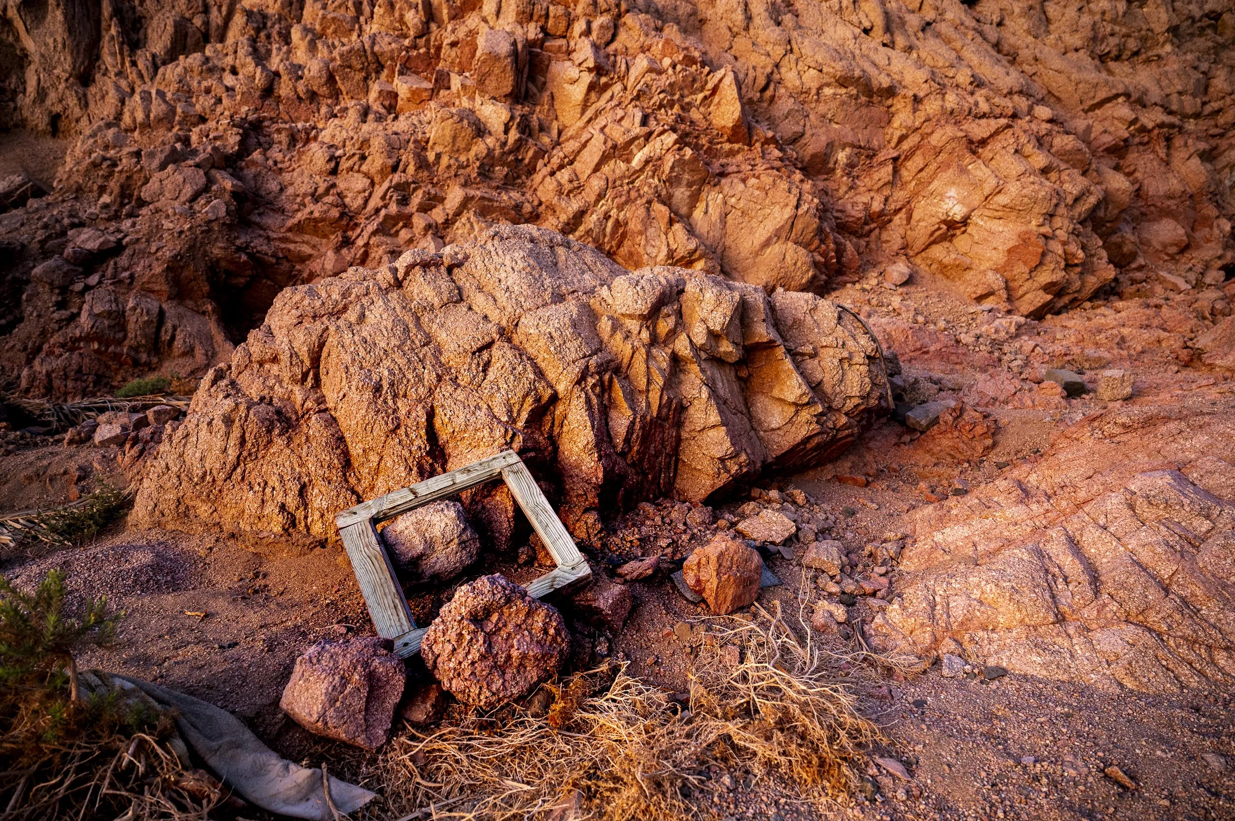 Rocks and boulders in desert landscape with a small wooden frame placed among them.
