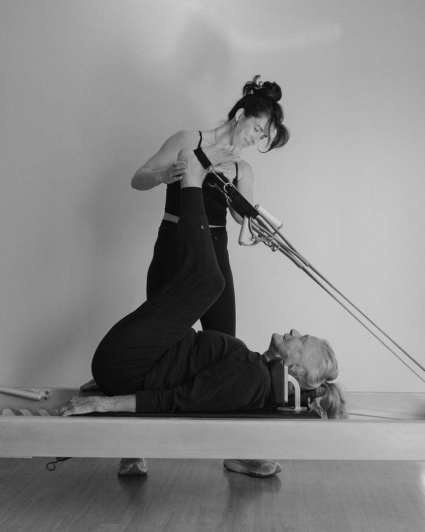A woman receiving physical therapy from a therapist who is using a resistance band while the patient lies on a specialized treatment table.