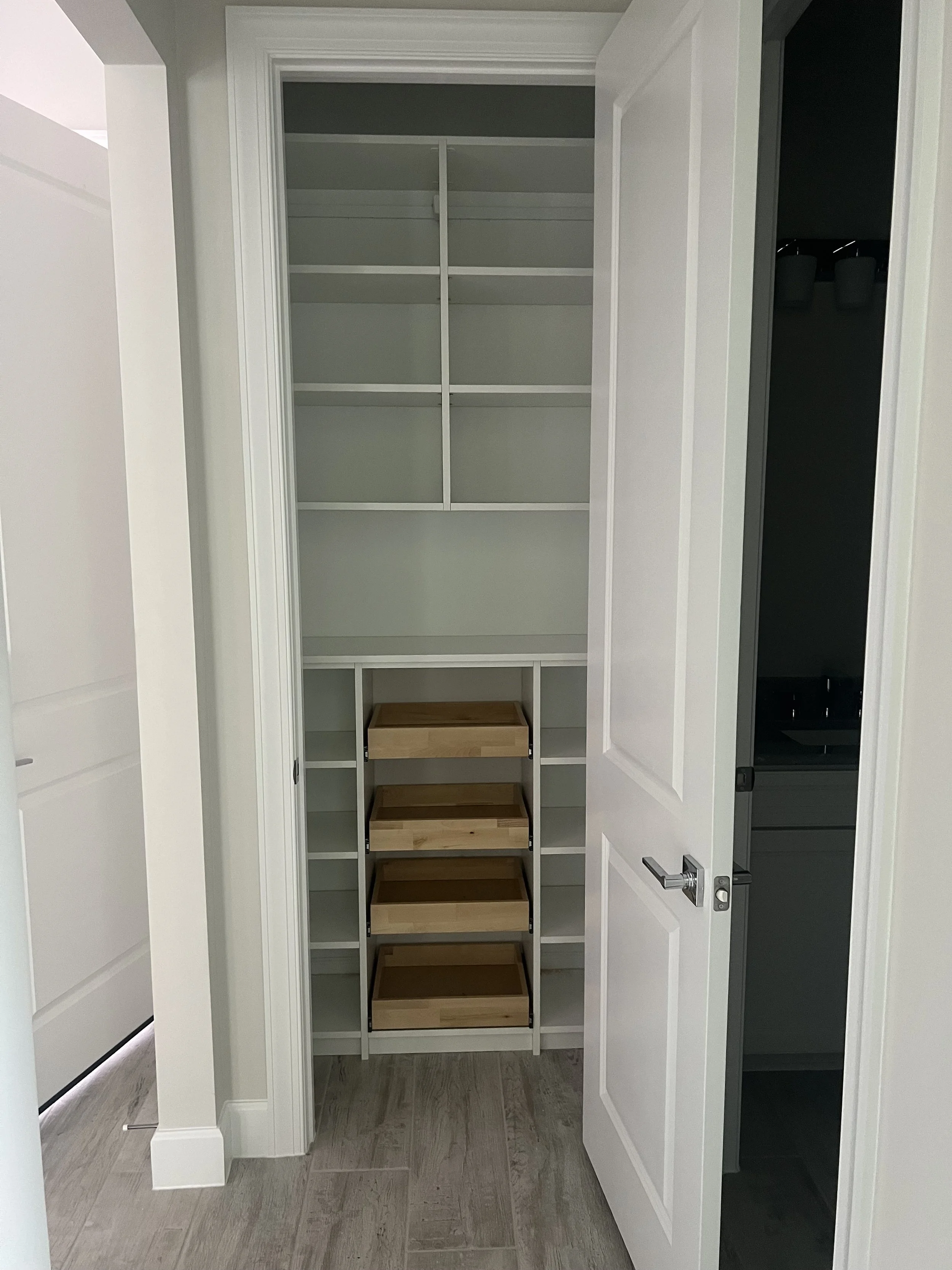 Empty closet with built-in shelves and four wooden storage bins in a modern home.