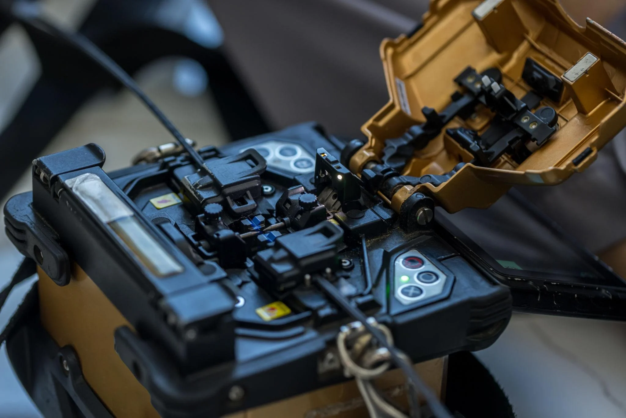 Close-up of an open electronic device with internal components and circuitry visible, with a yellowish-brown casing and various black mechanical parts.