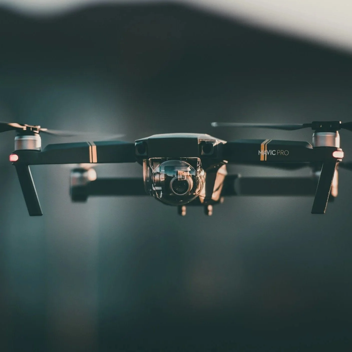 Close-up of a drone with a camera, flying indoors against a dark background.