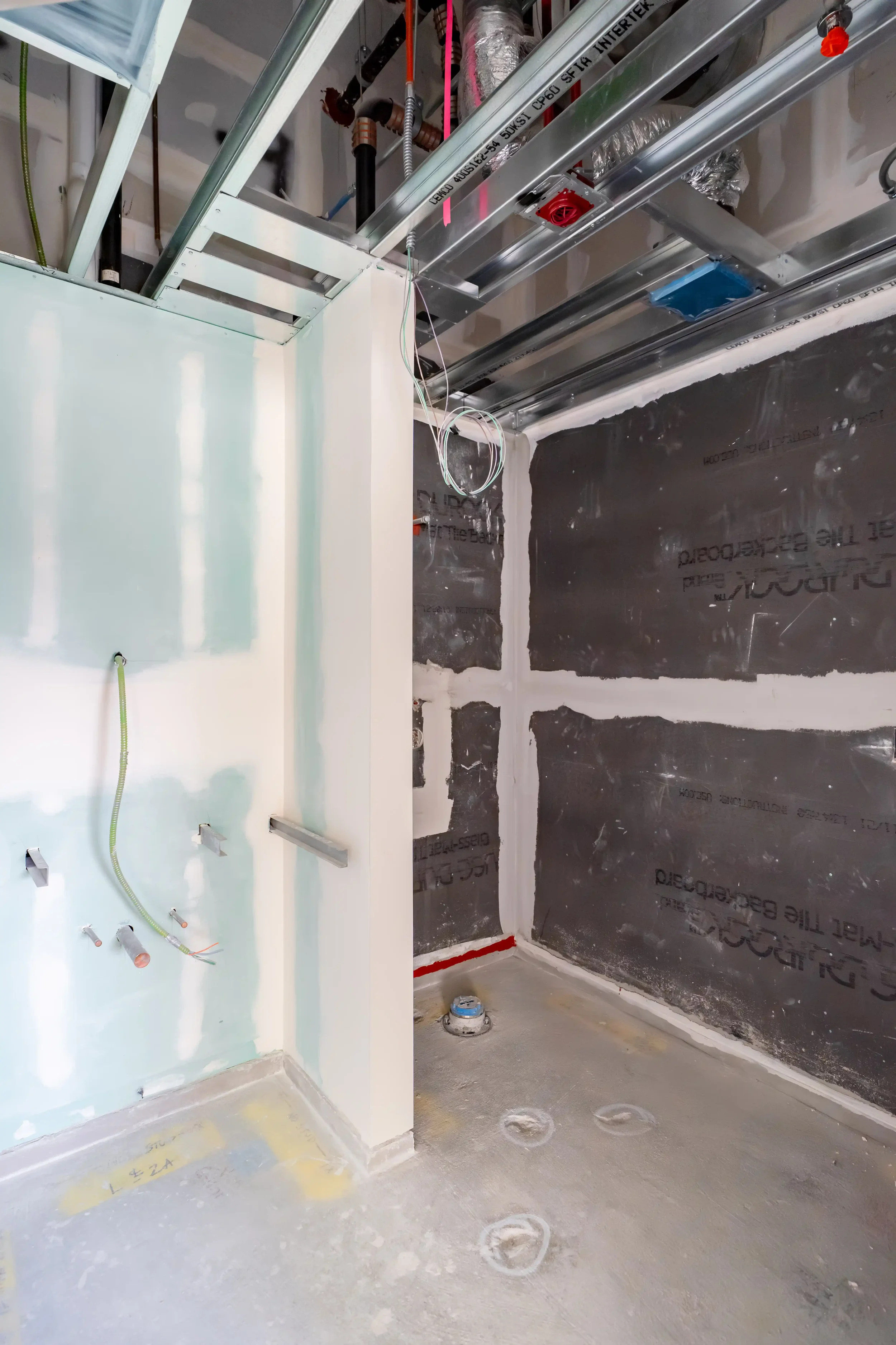 Construction site with exposed wiring, plumbing, and ductwork in an unfinished room.
